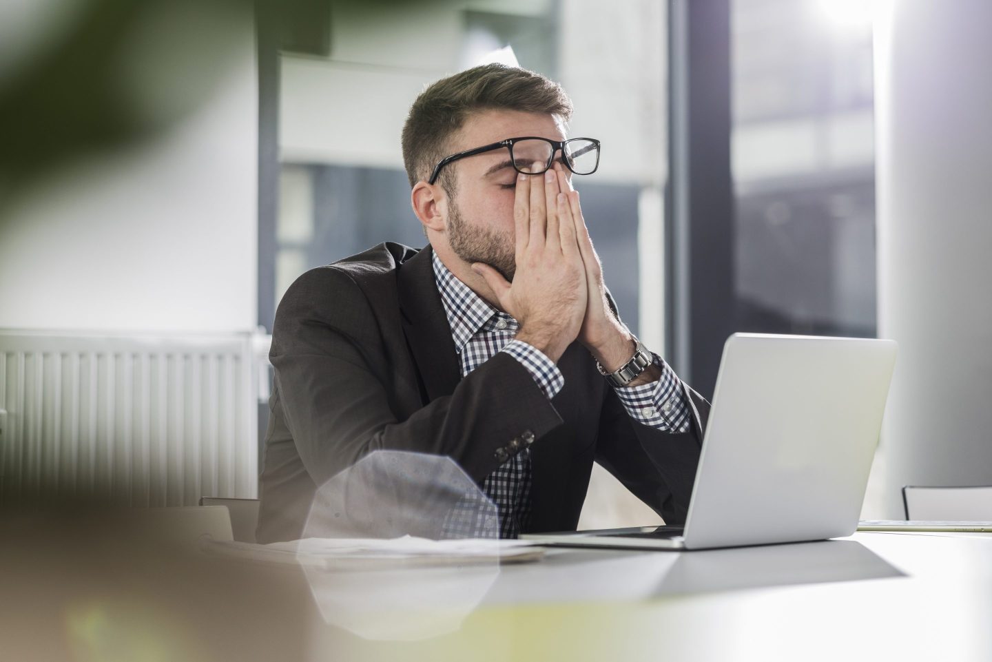 A man sitting at his laptop looking burned out.