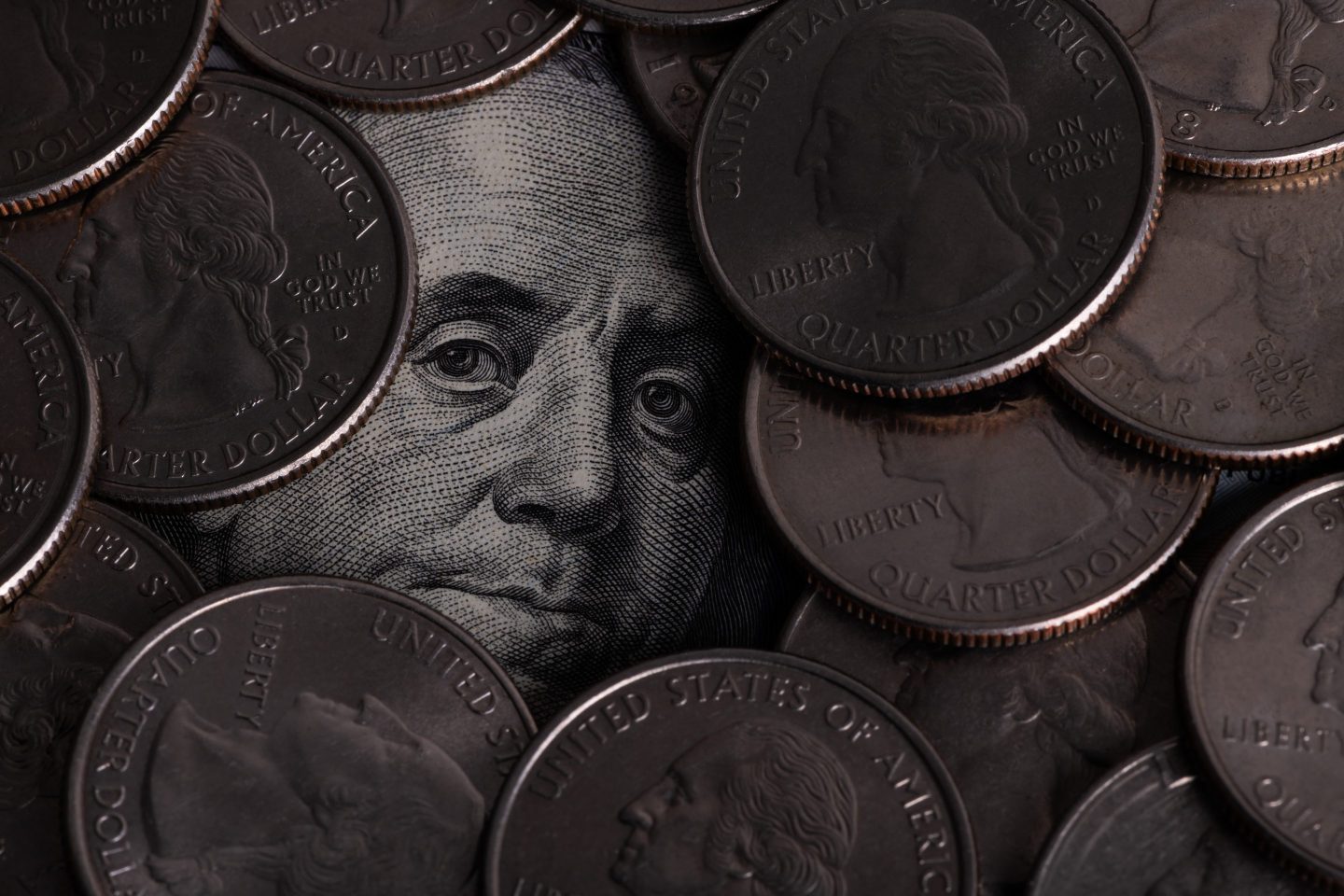 Benjamin Franklin's face from a $100 bill surrounded by quarters