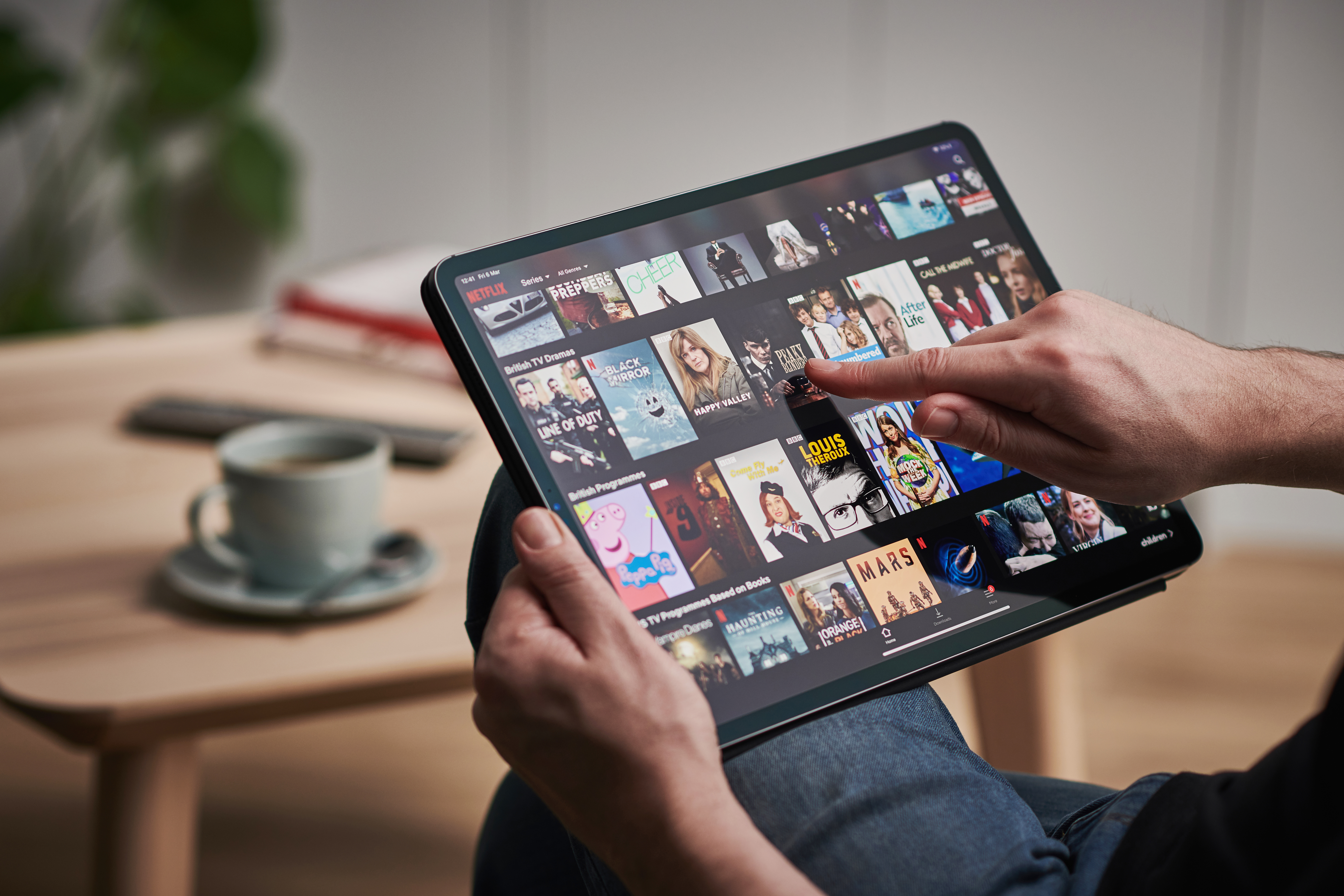 A man is seen scrolling through Netflix on an iPad.