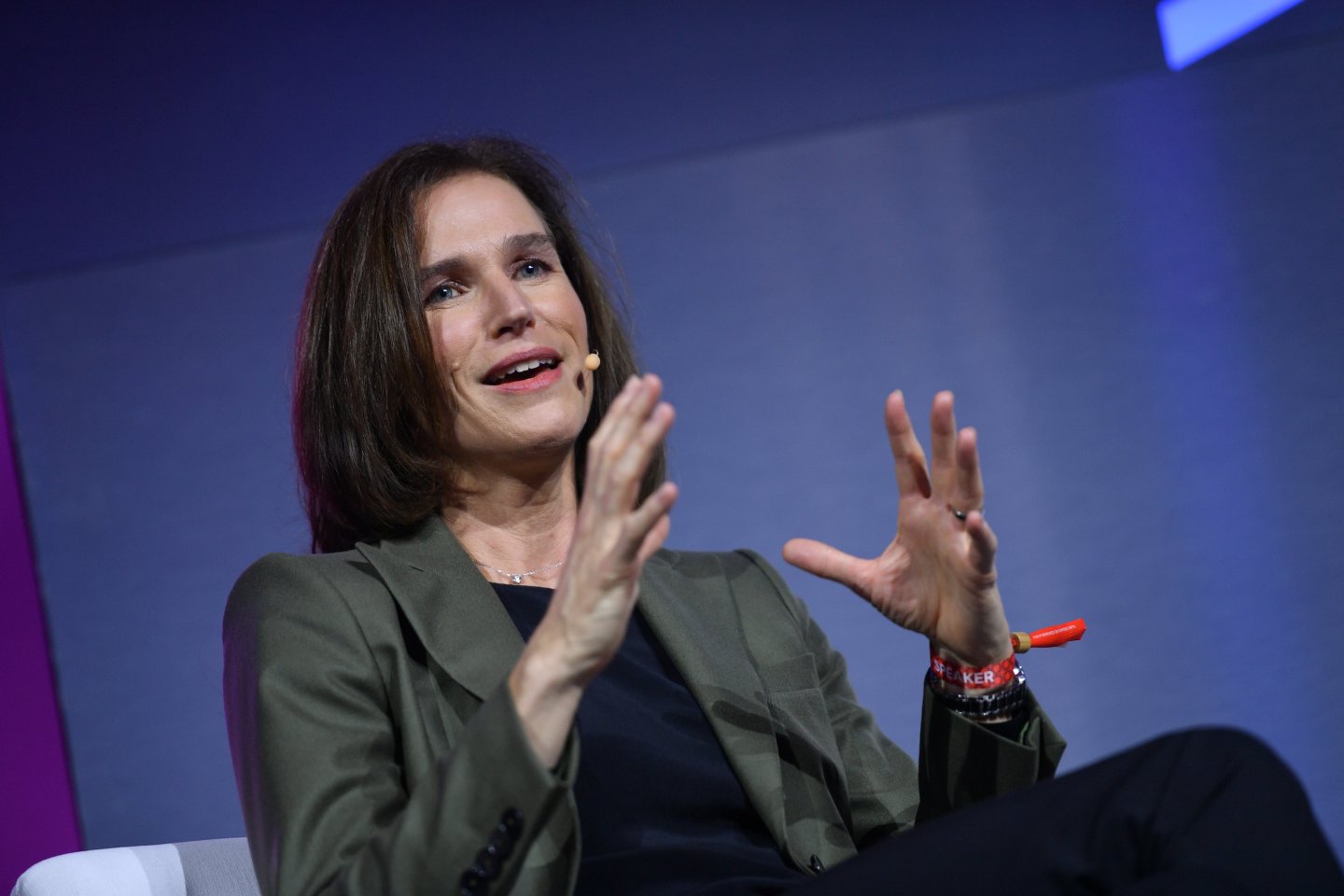A woman with dark hair in a blazer addresses a crowd