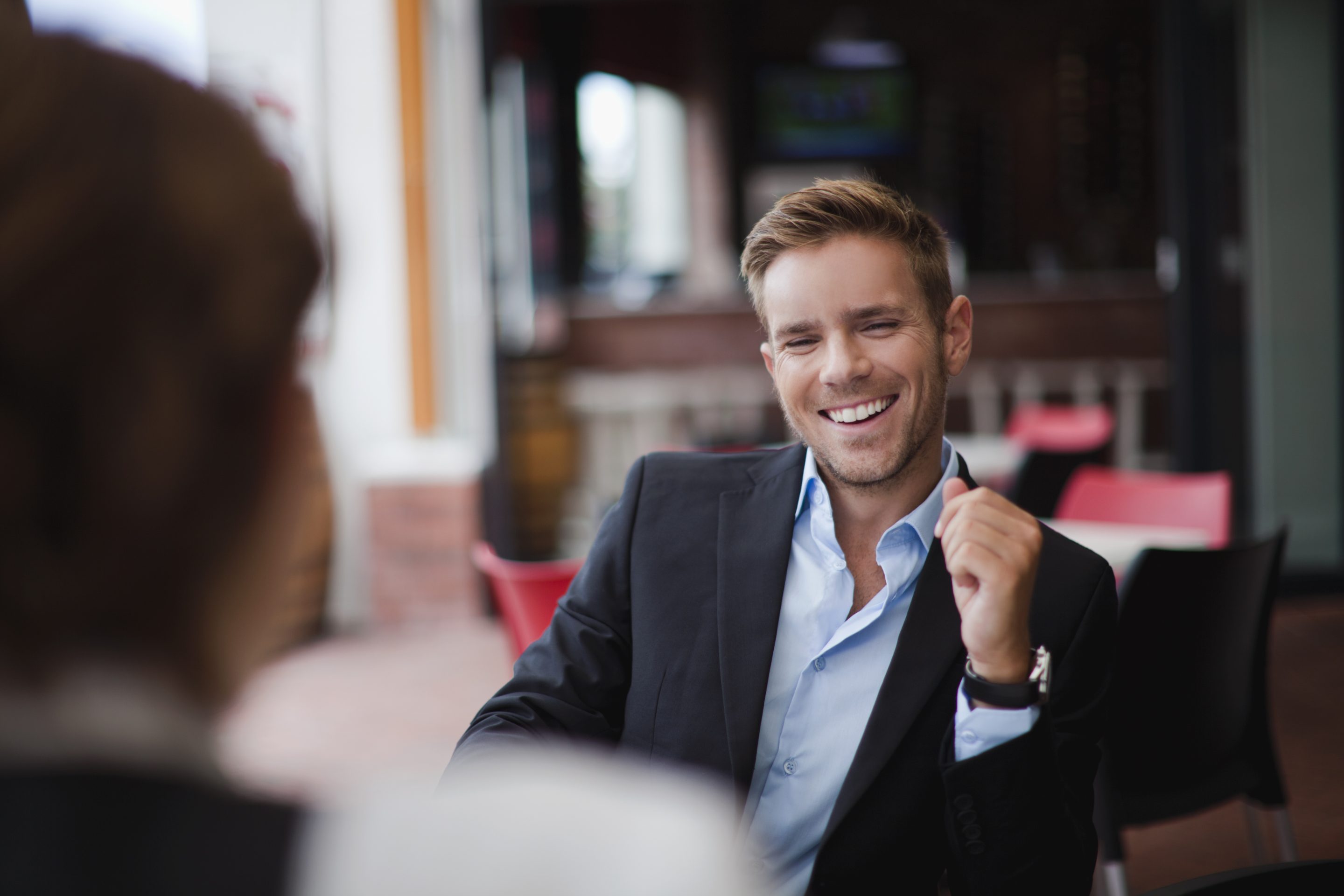 A man in a suit laughs to a colleague