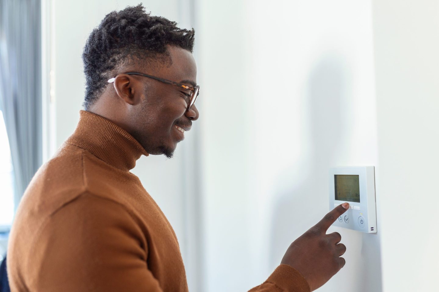 Man using thermostat while wearing sweater