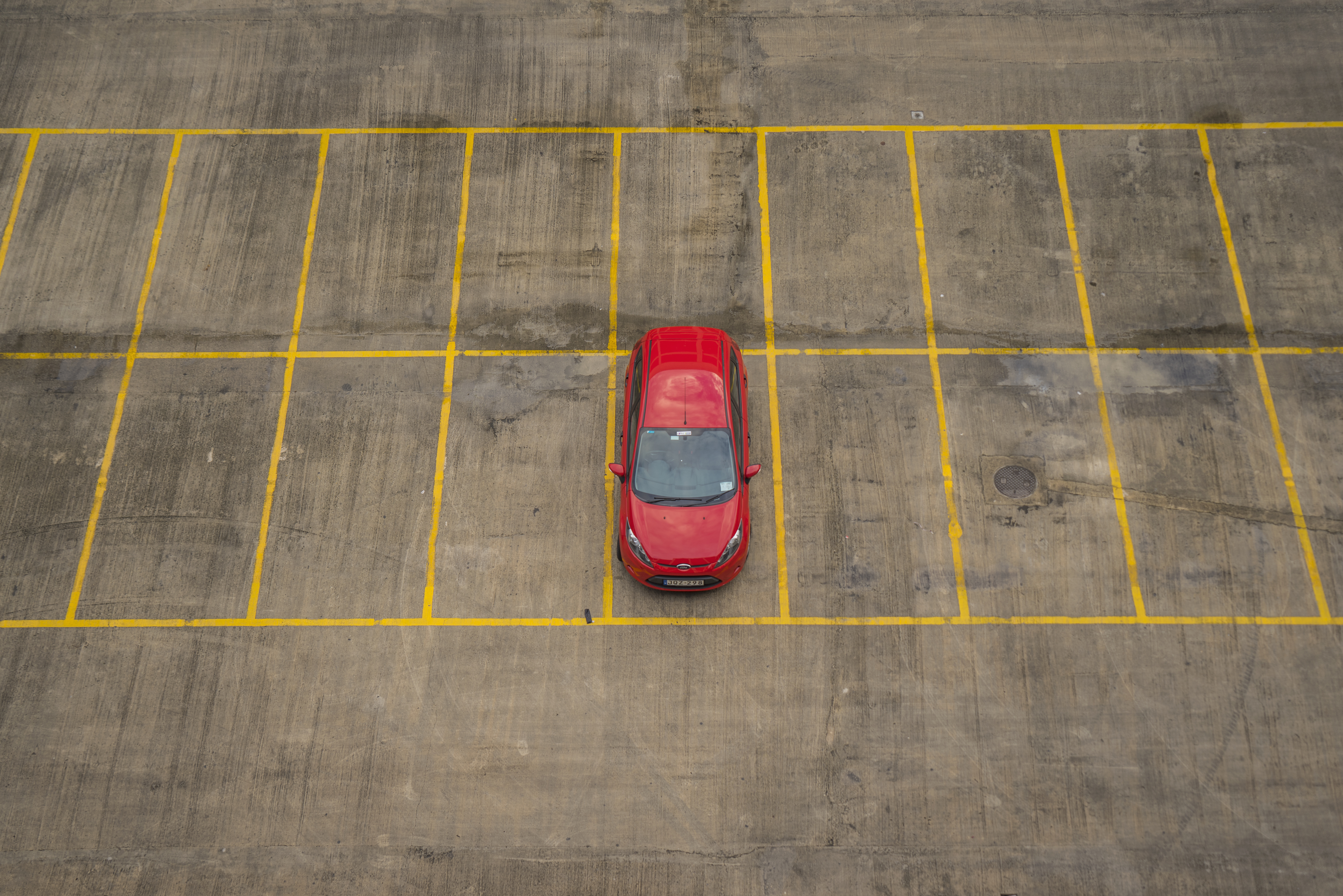 A red car in an empty parking lot.