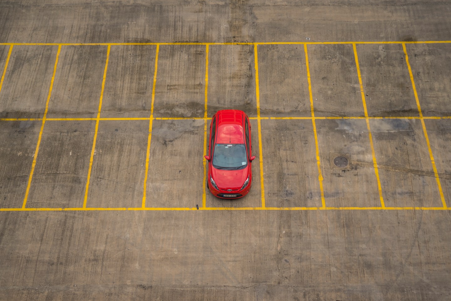 A red car in an empty parking lot.