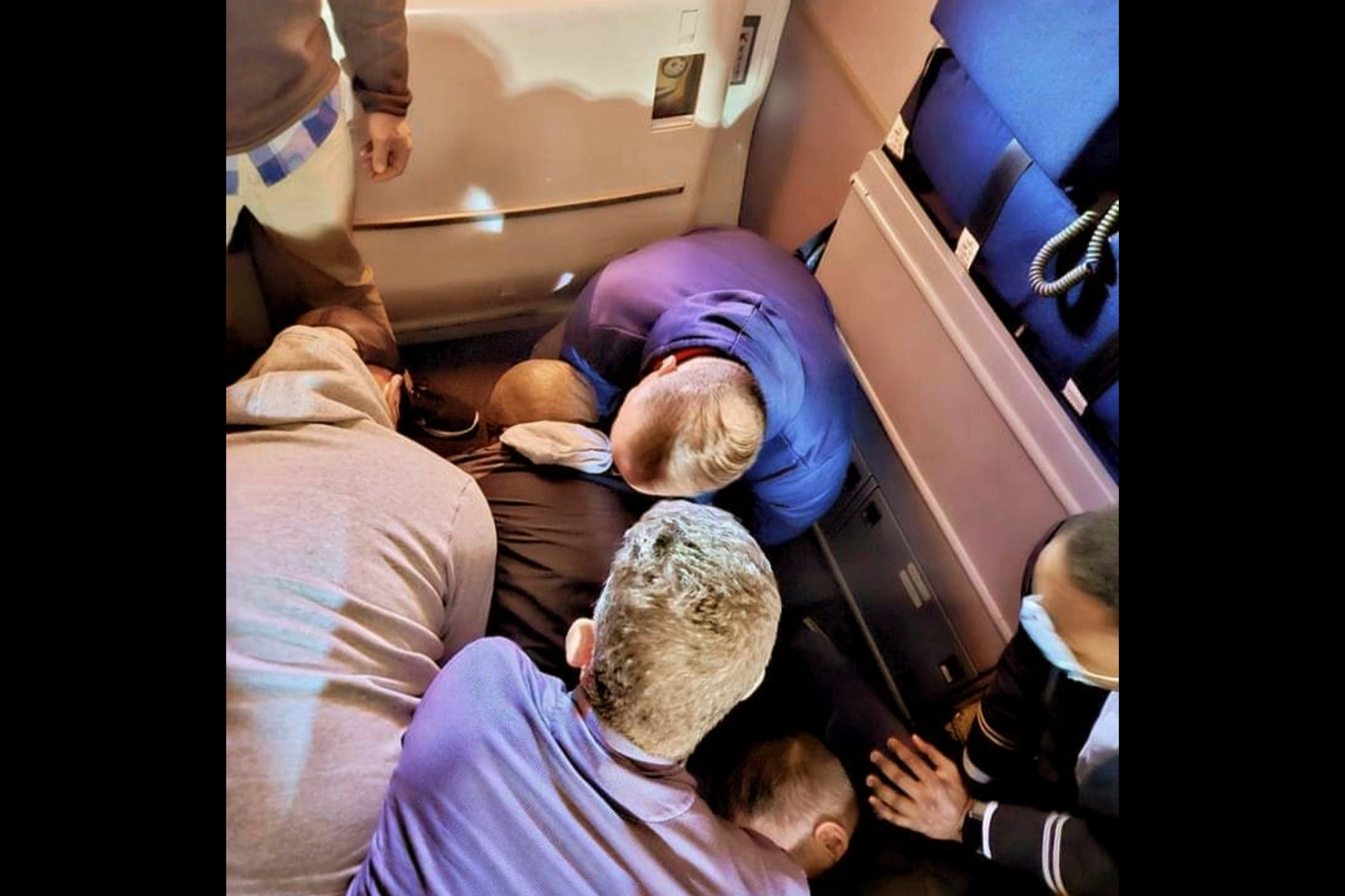 This image provided by Simik Ghookasian shows passengers and crew members restraining a man who according to federal authorities tried to open an airliner’s emergency door and tried to stab a flight attendant on a weekend flight from Los Angeles to Boston on Sunday, March 5, 2023.  