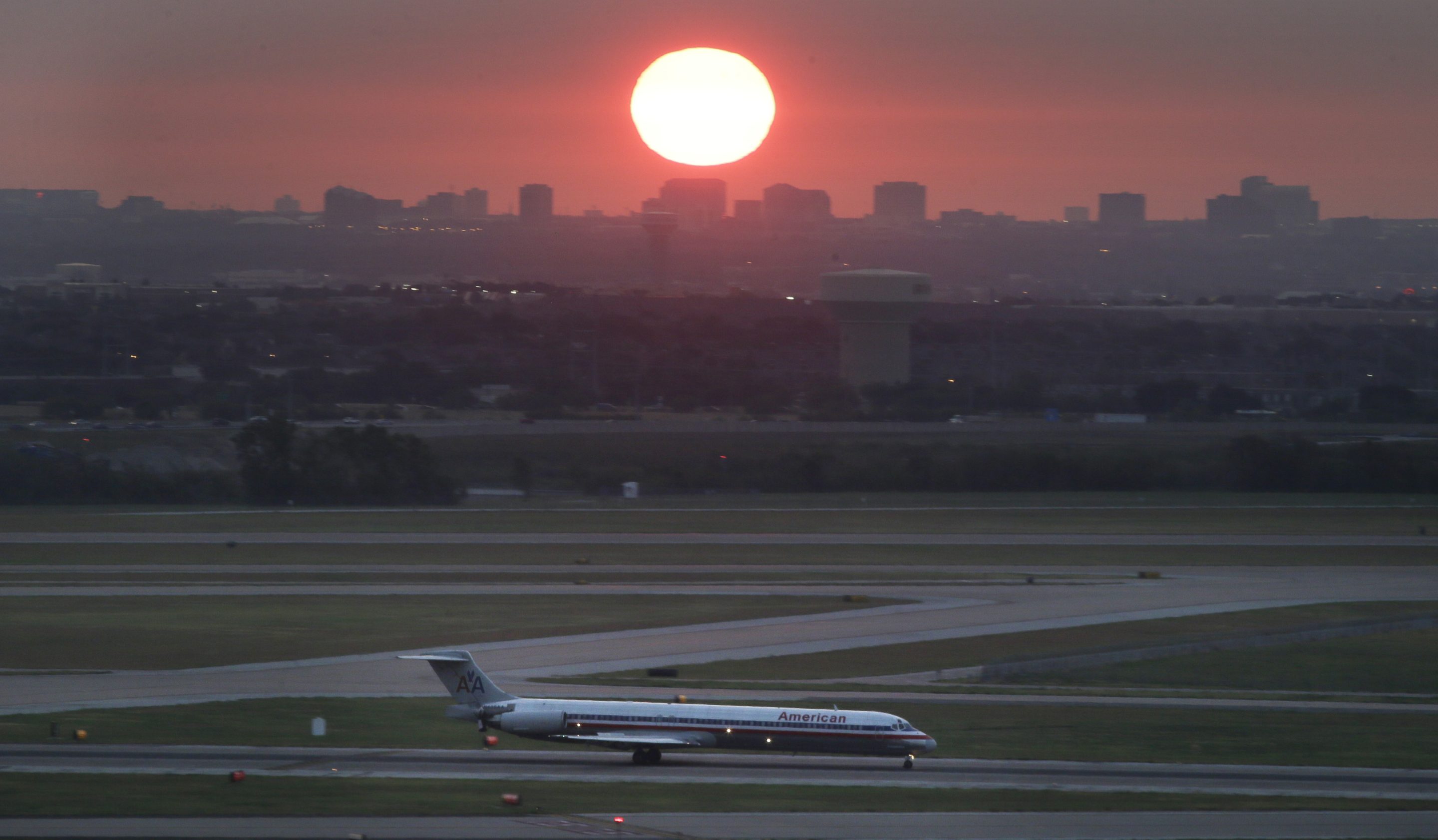 In this Aug. 26, 2015 file photo, an American Airlines jet taxis on a runway as the the sun rises in the east sky looking from the Dallas-Fort Worth International Airport in Grapevine, Texas.