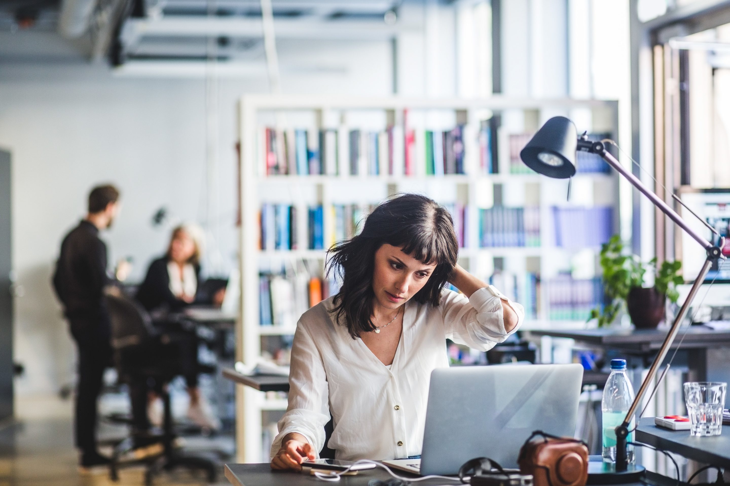 A woman looking at laptop while sitting in office.