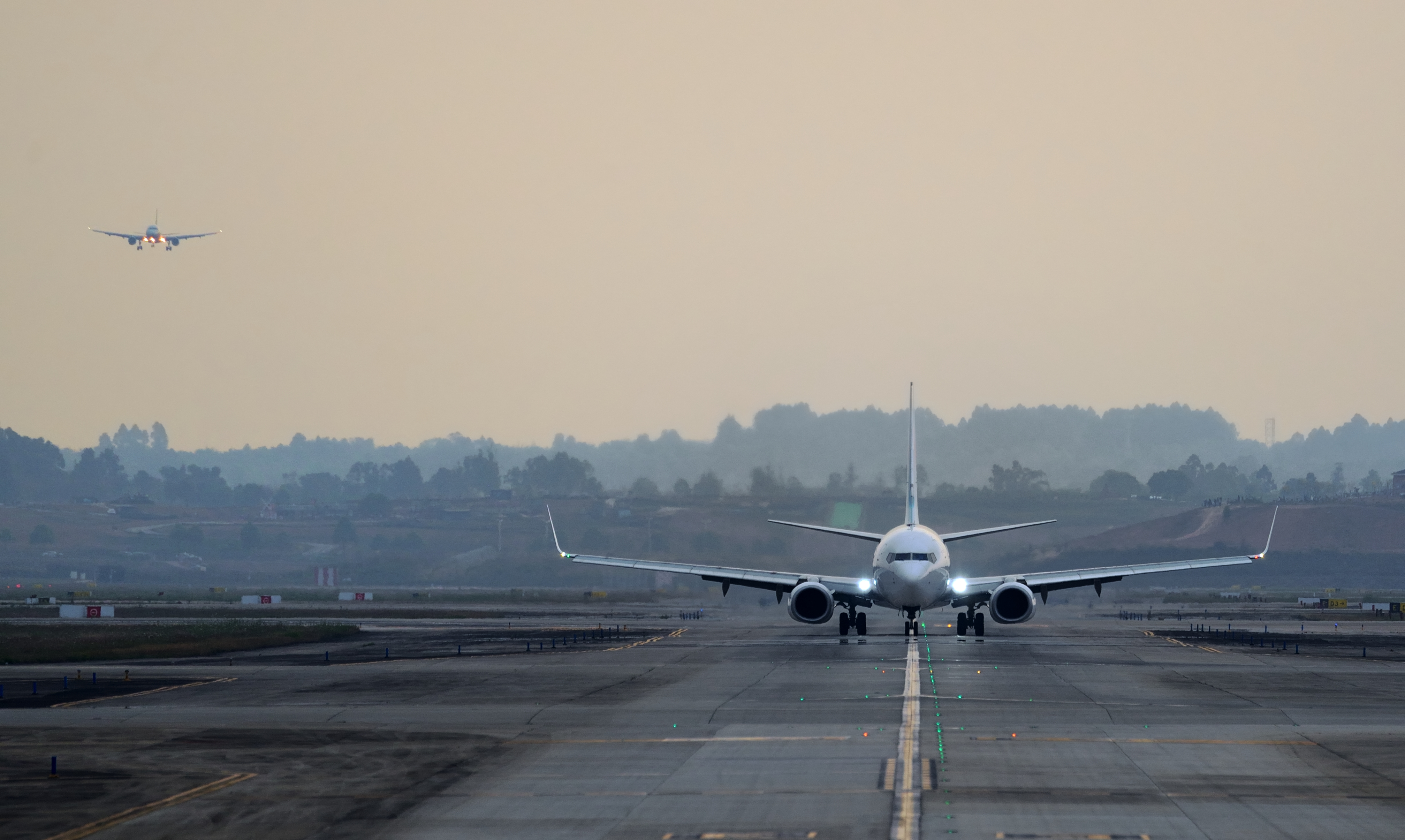 A plane lands on a runway in low light