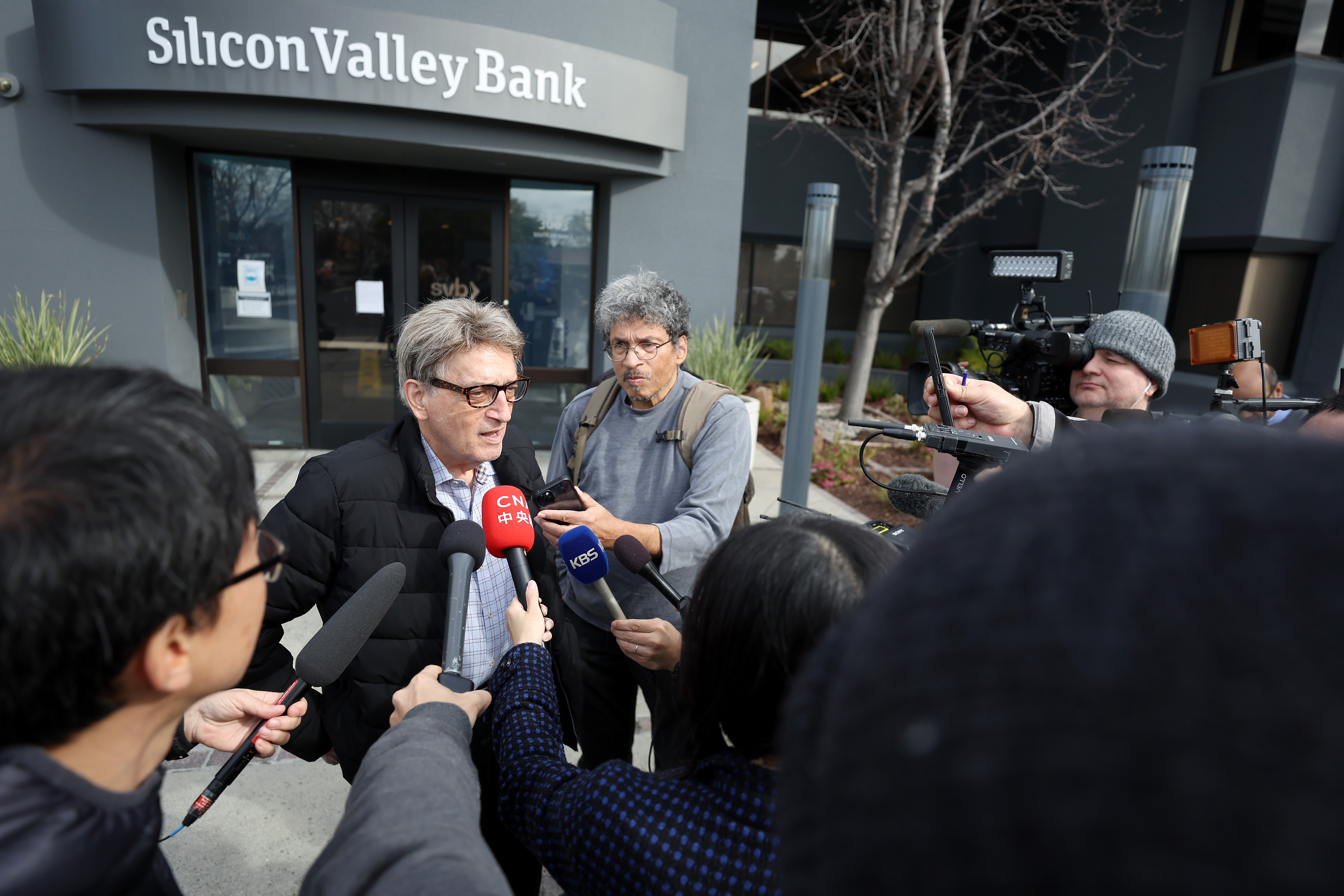 Members of the media interview a Silicon Valley Bank customer outside of the bank office on March 13, 2023 in Santa Clara, California.