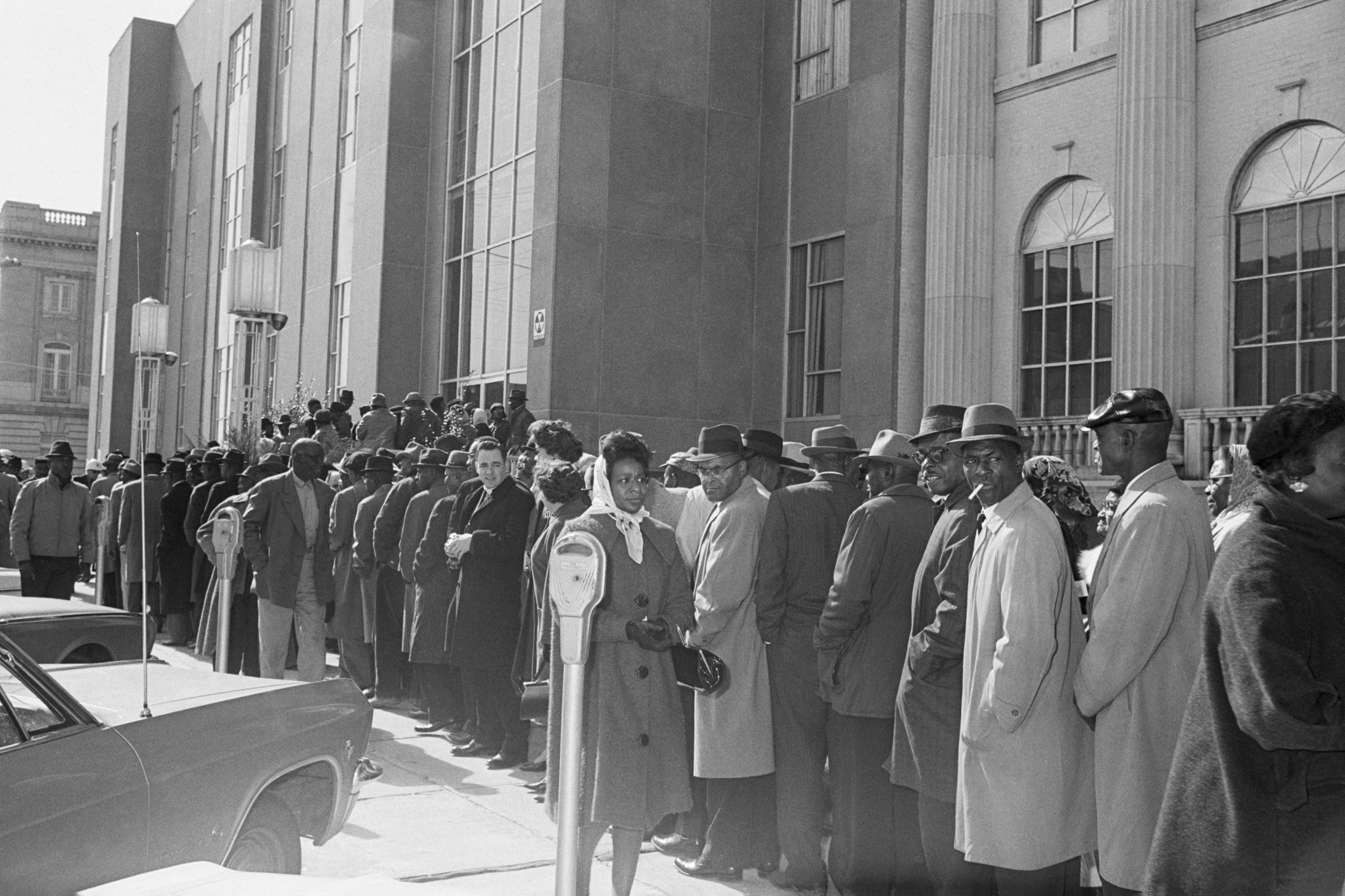 African Americans, led by Reverend Martin Luther King Jr, line up in front of the Dallas County Courthouse in Selma, Alabama to register to vote.