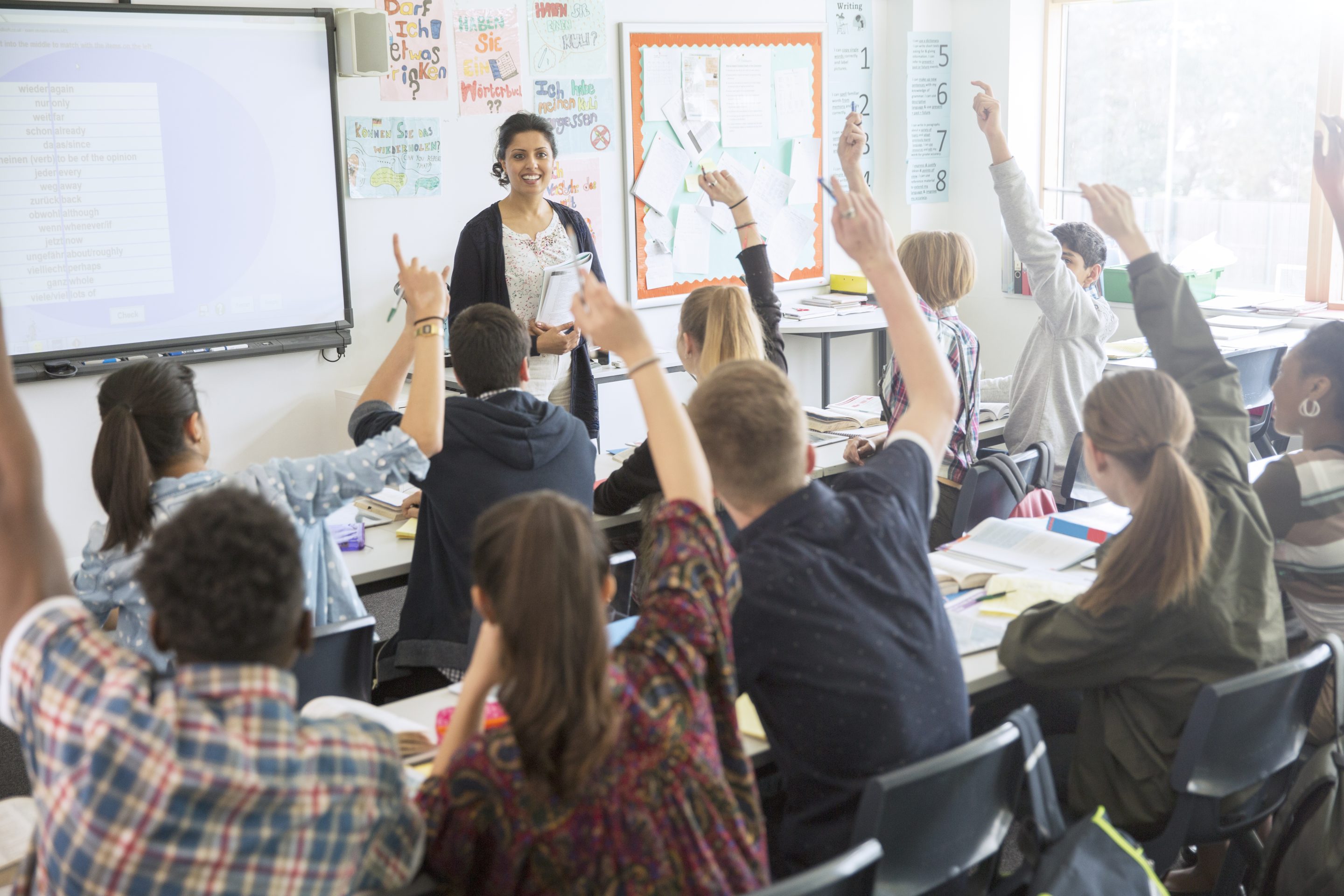 A classroom with students raising their hands