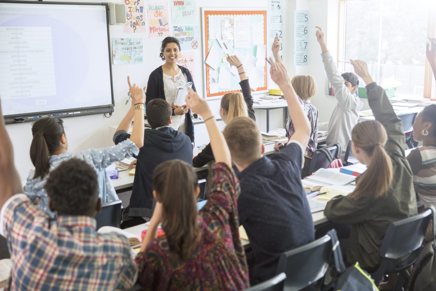 A classroom with students raising their hands