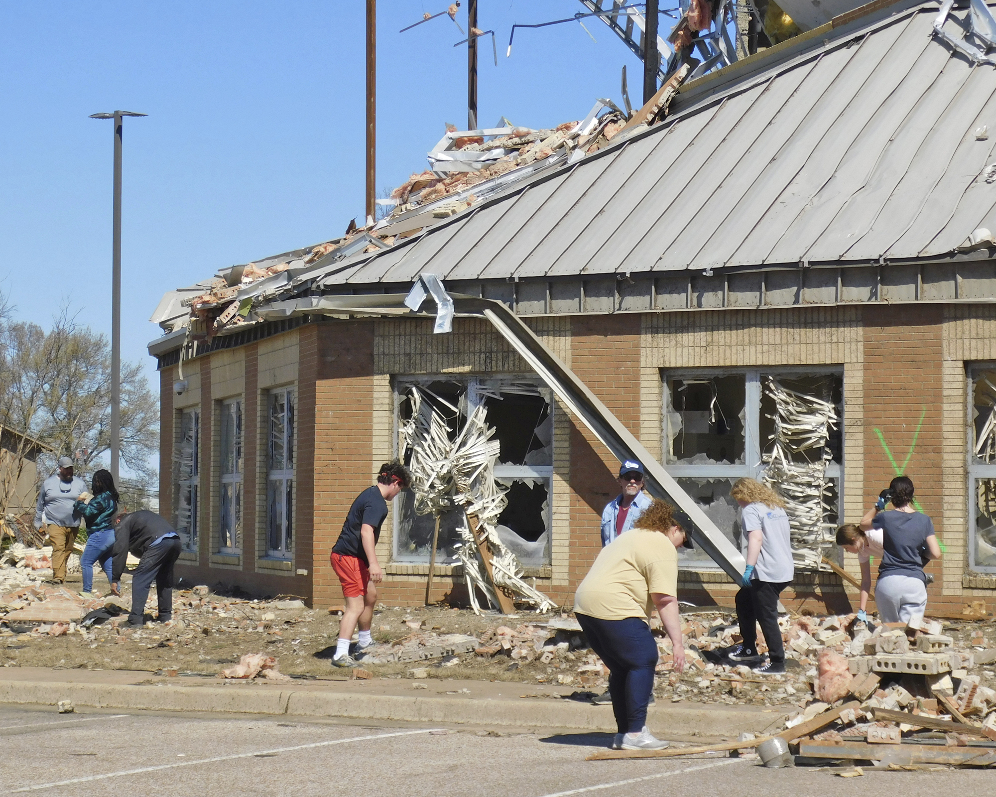 Volunteers clean up at Wynne High School, Saturday, April 1, 2023, near the front entrance of the school on E. Jackson Avenue in Wynne, Ark., following severe weather the previous night.