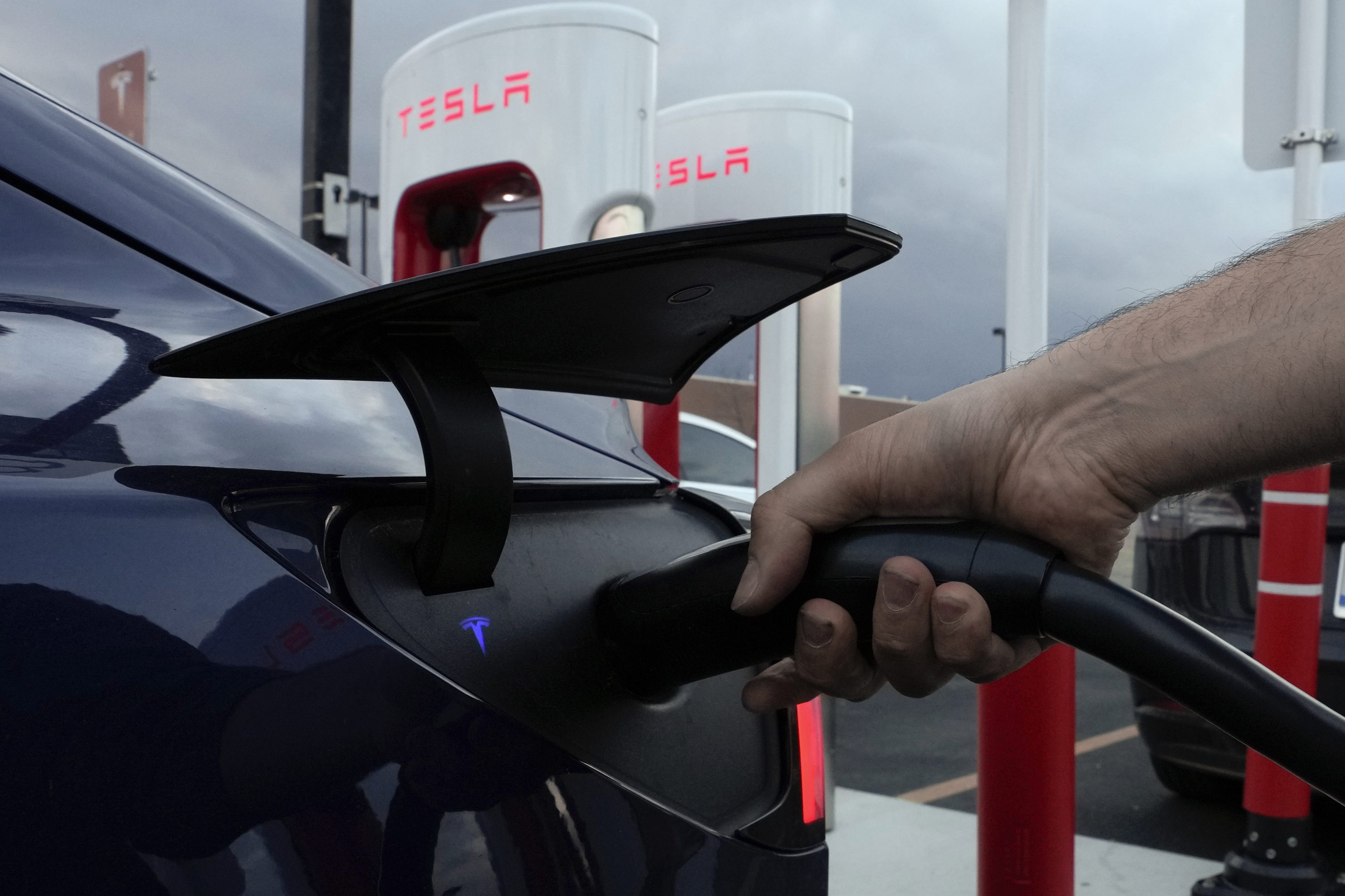 A motorist charges his electric vehicle at a Tesla Supercharger station in Detroit, on Nov. 16, 2022.