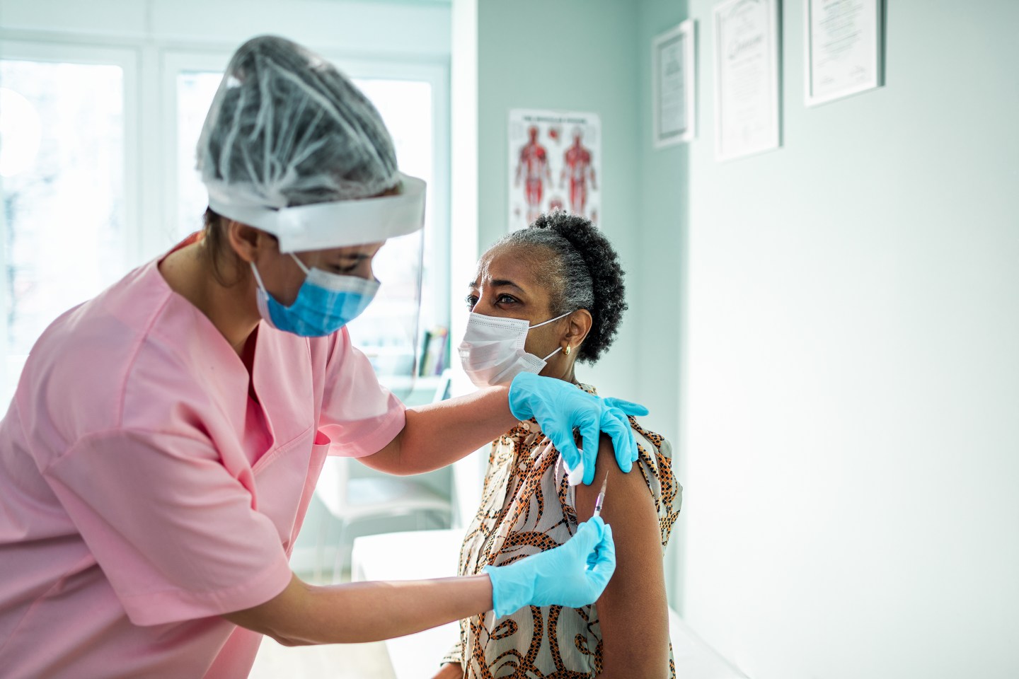 Photo of nurse administering a vaccine into an older woman's arm.