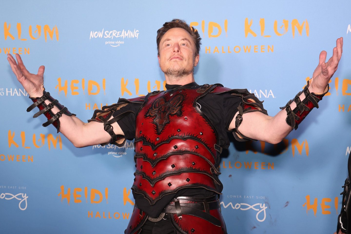 Elon Musk in a costume suit of armor poses for photos.