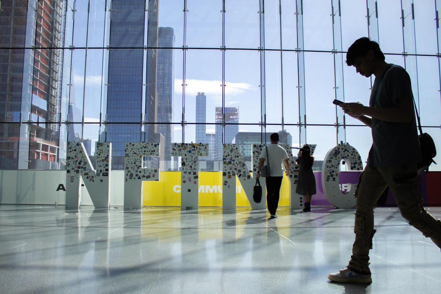 A passerby walks in front of the NFT.NYC sign.