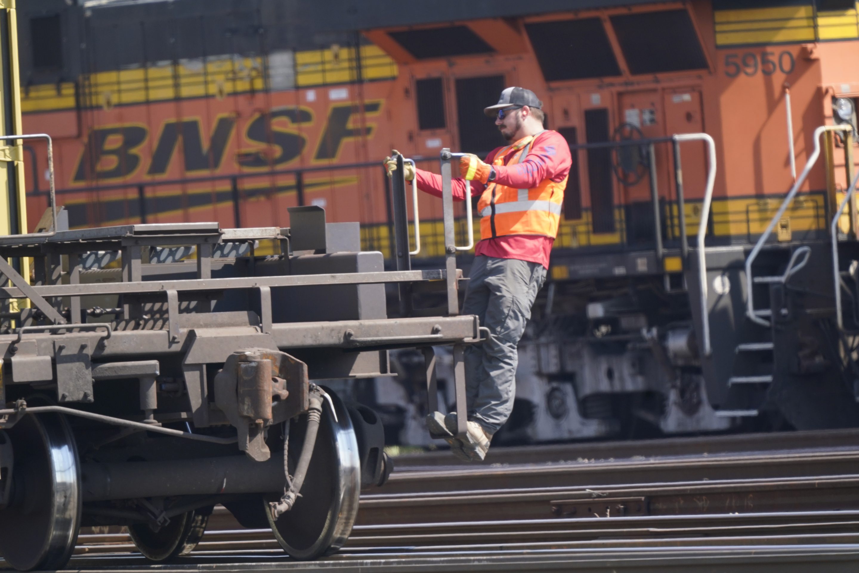 A worker rides a rail car at a BNSF rail crossing in Saginaw, Texas, Wednesday, Sept. 14, 2022.