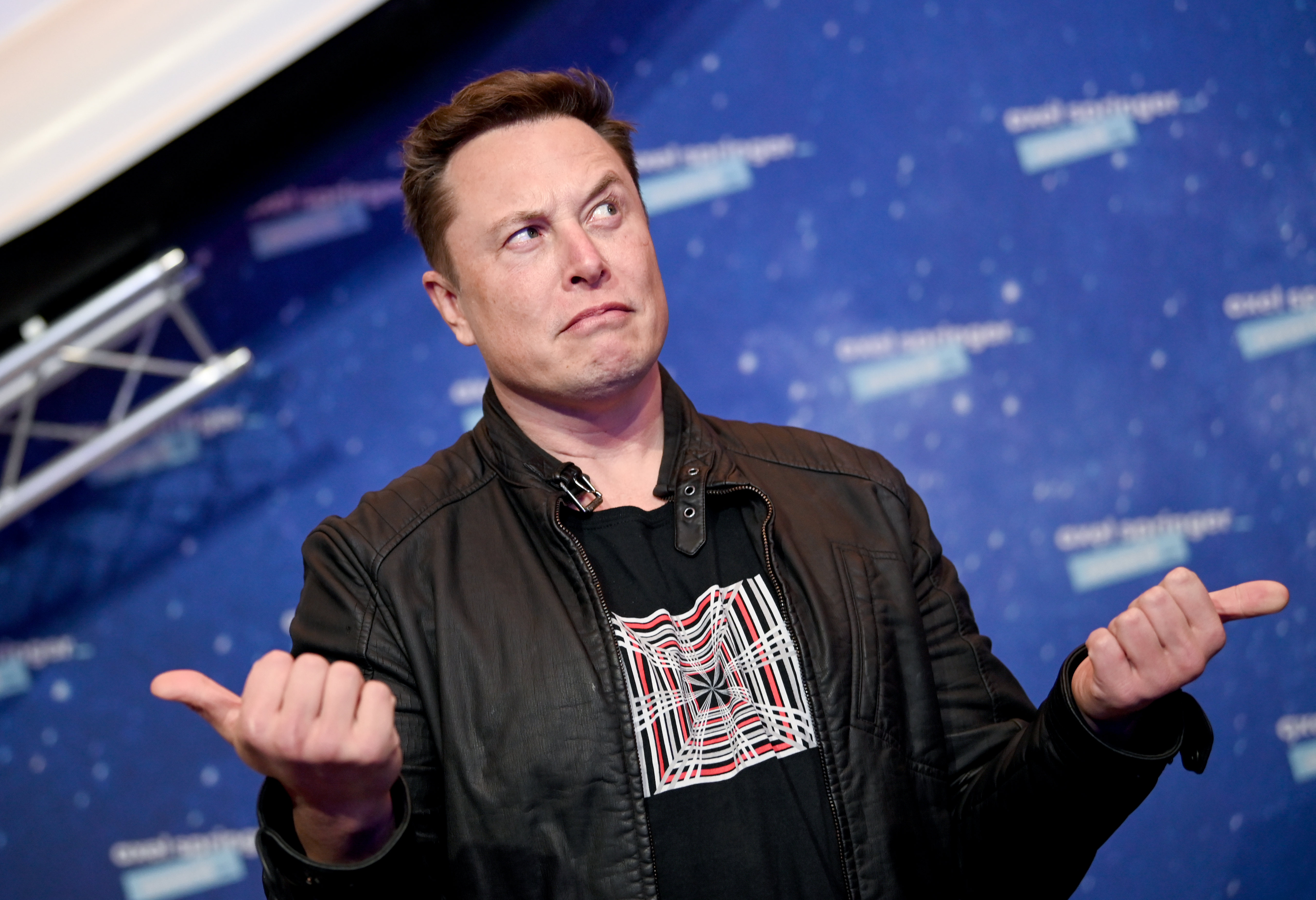 Elon Musk shrugging with thumbs pointed outwards