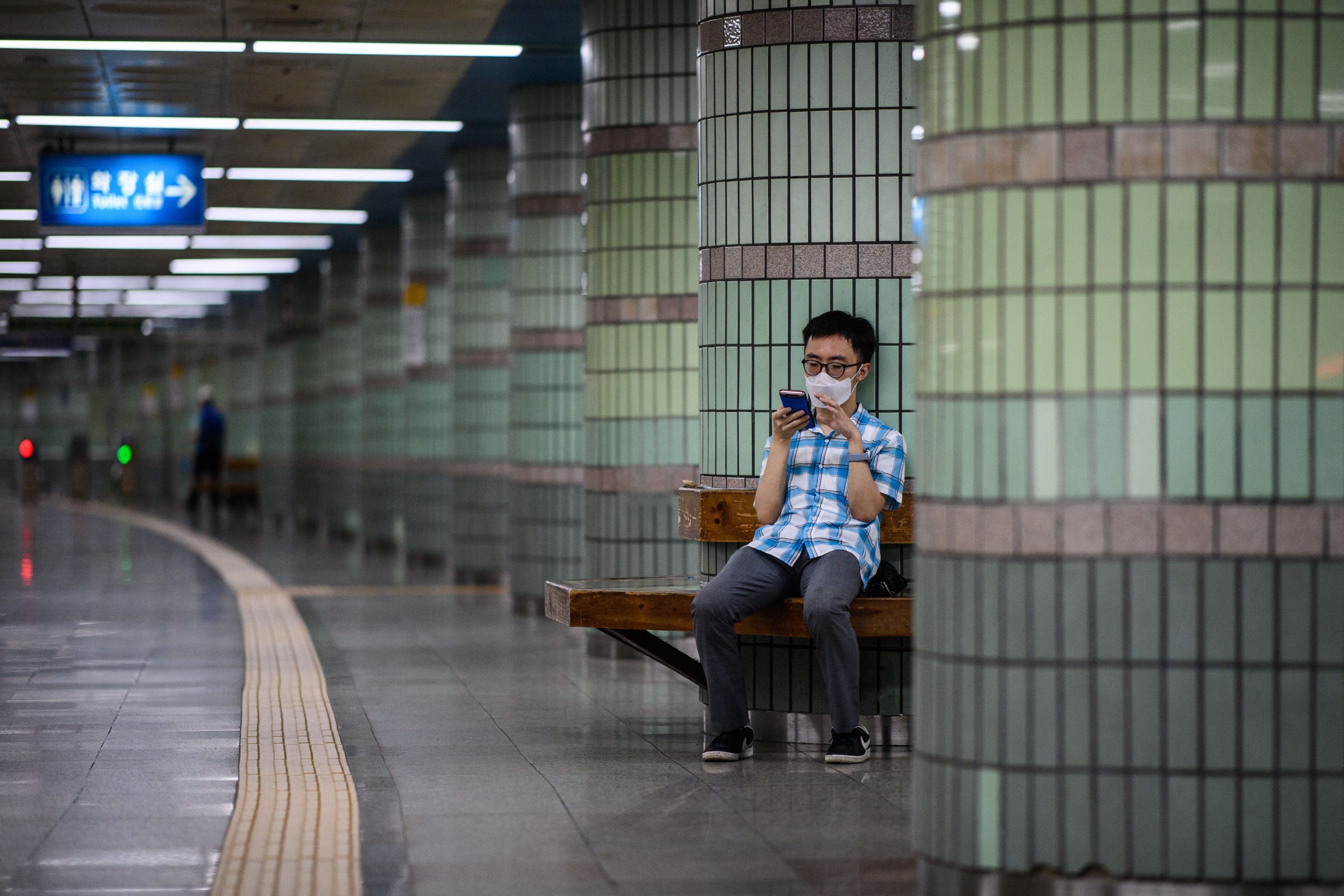 A commuter absorbed by his phone in a train station of the Seoul Metropolitan Subway in Seoul.