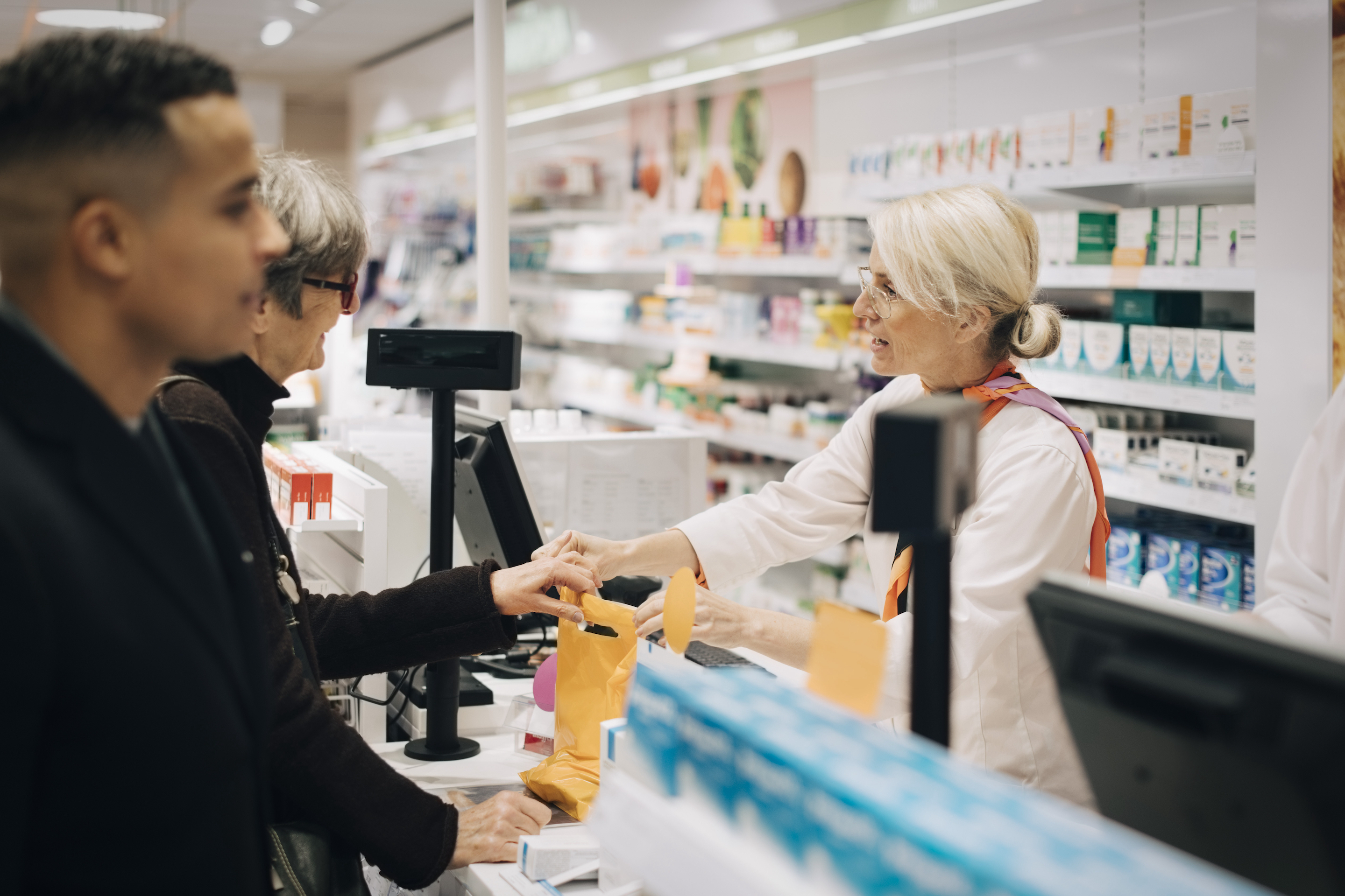 A pharmacist waiting on a customer at a pharmacy counter