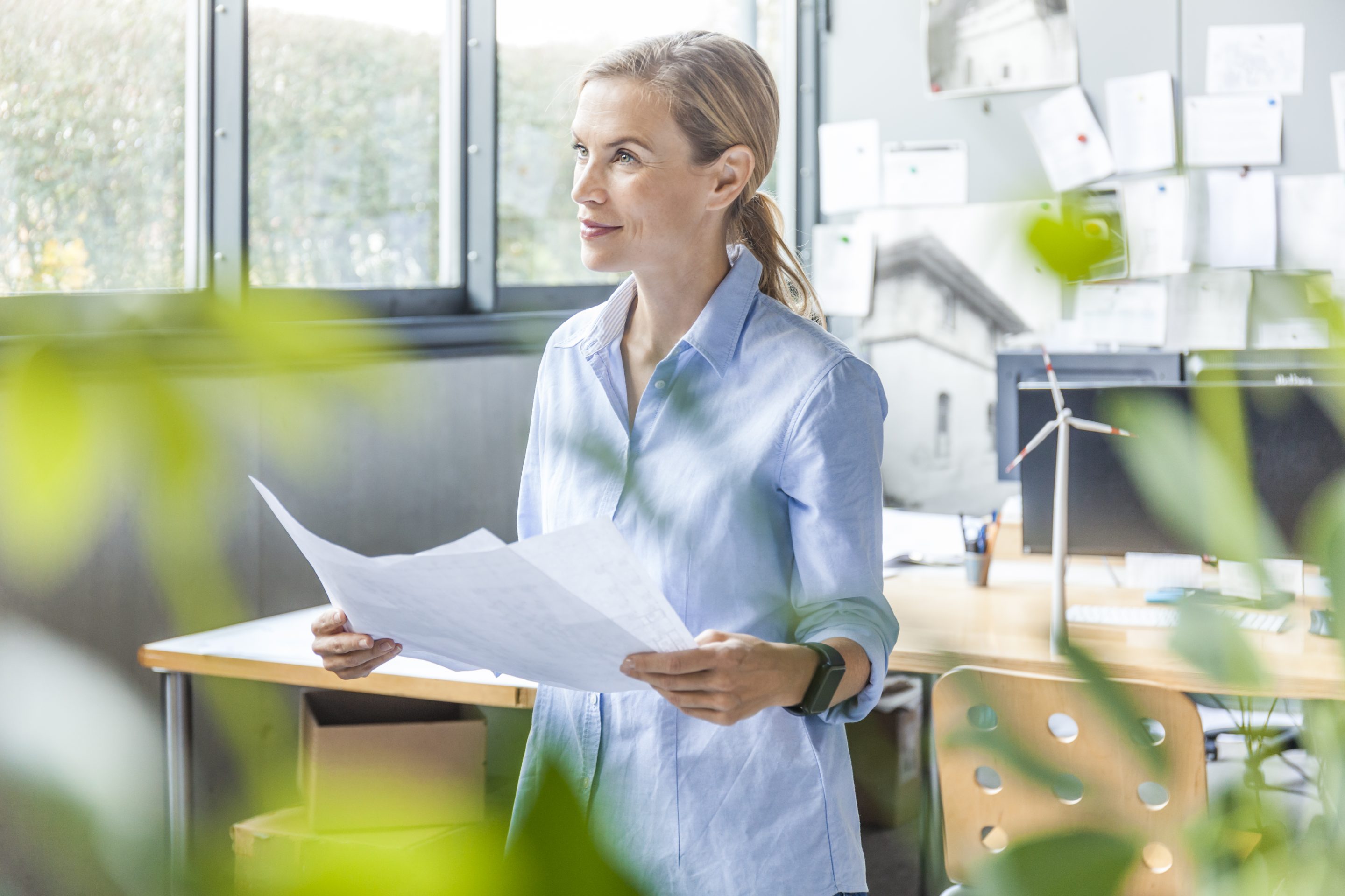 Woman in office working on plan with wind turbine model on table