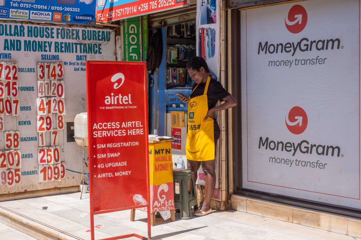 A worker at a mobile money kiosk alongside a currency exchange bureau in Kampala, Uganda.