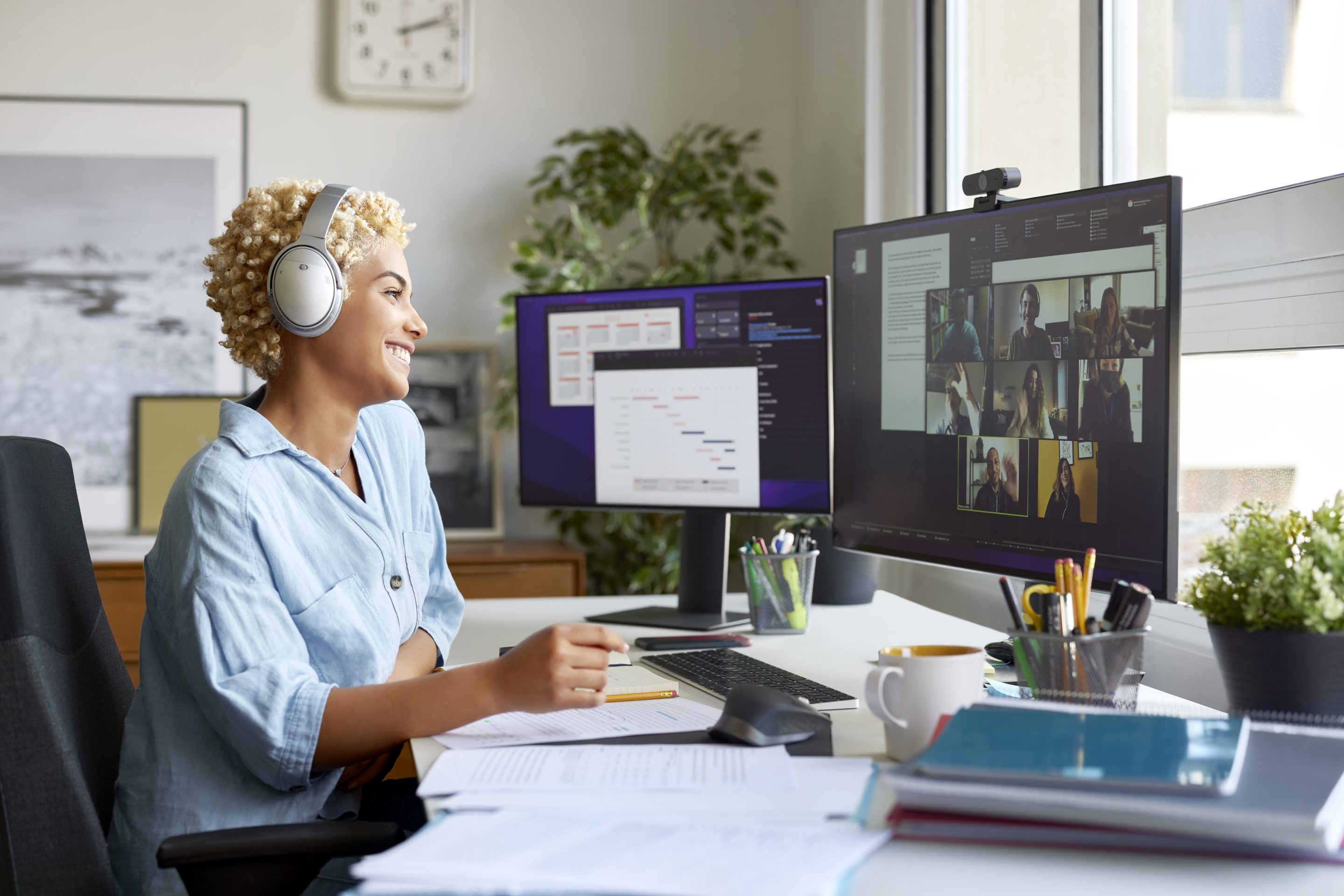A cheerful businesswoman working from home while looking at a video meeting on her computer monitor