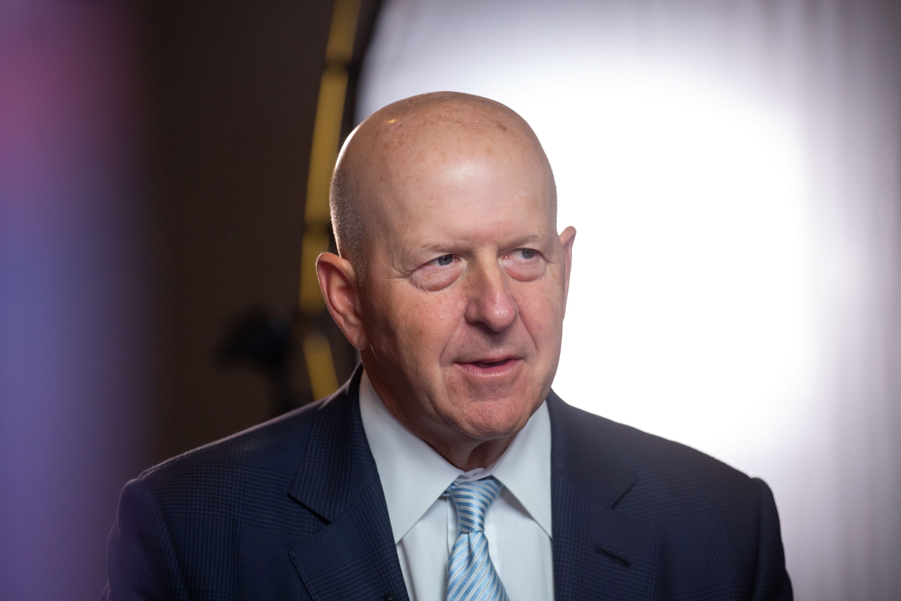 bald man wearing a suit and blue tie