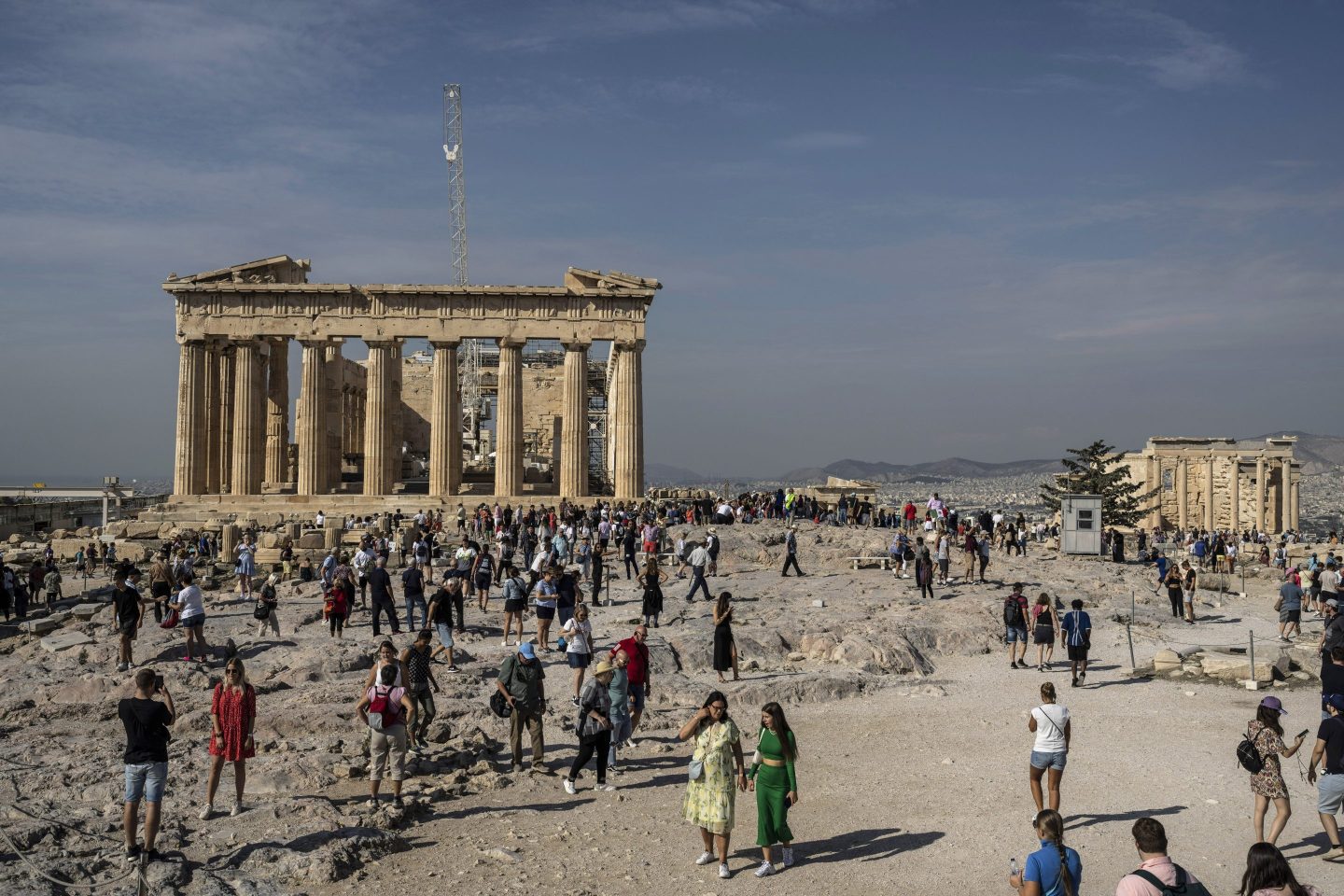 Tourists visit the Acropolis hill with the 2,500-year-old Parthenon temple on the left.