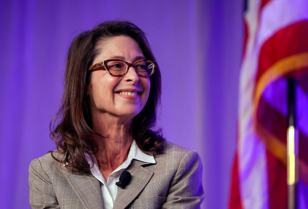 woman in professional clothing and eyeglasses smiling