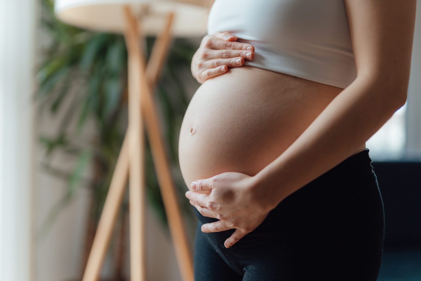 side view close-up of pregnant woman touching her belly.