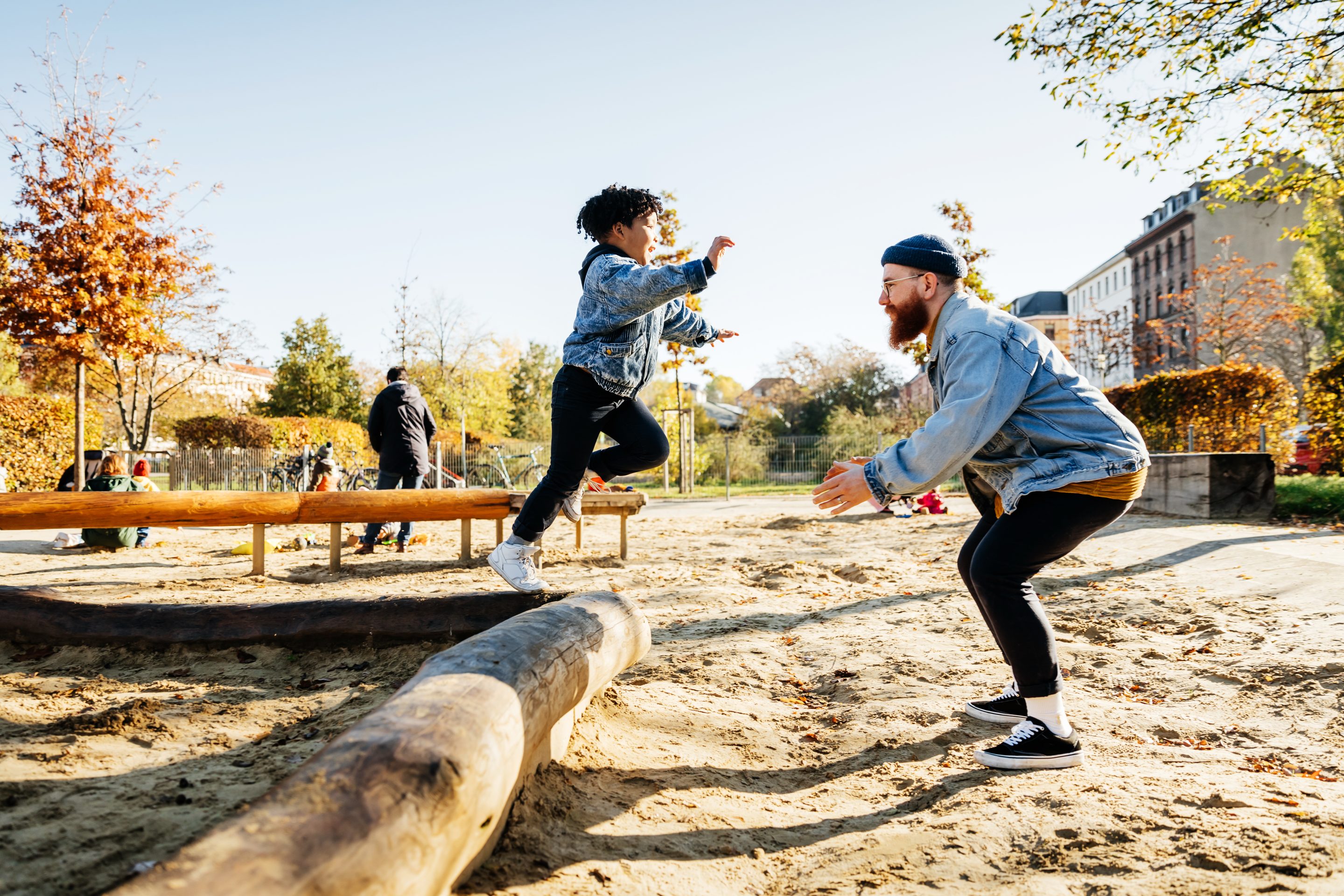 Young Boy Leaping Into Father Arms In Playground