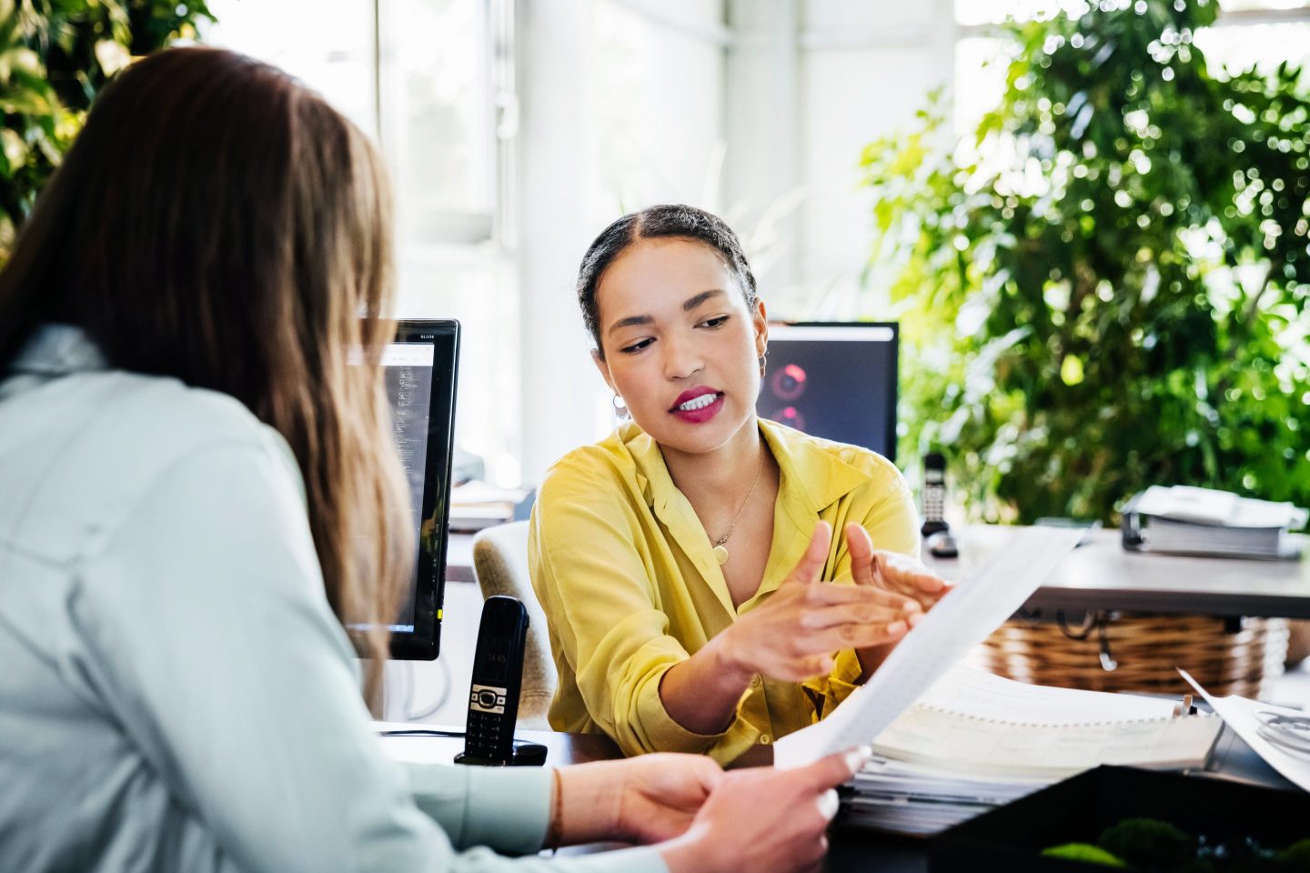 two women in professional clothing look over paperwork