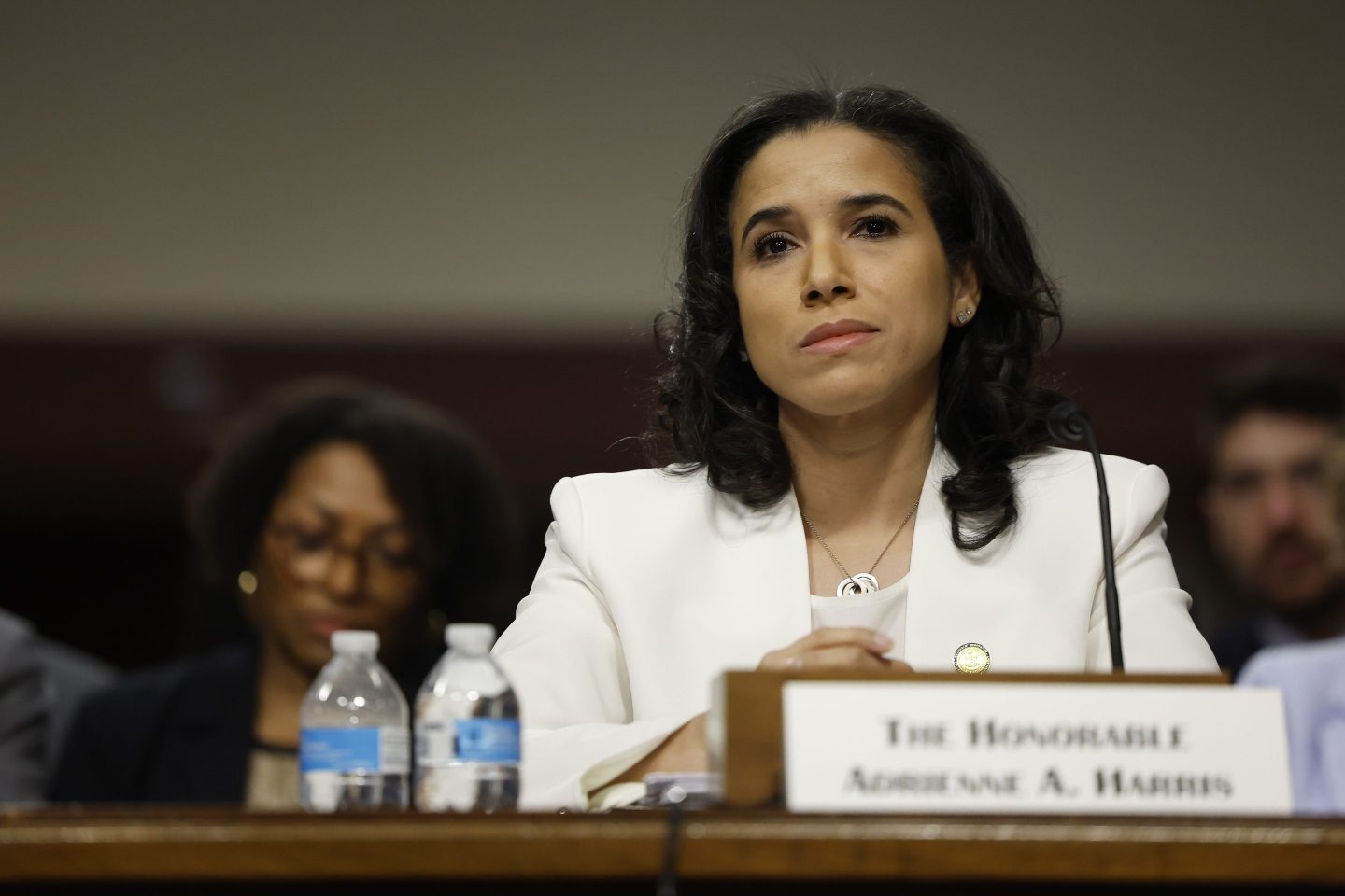 Woman wearing white suit jacket sitting in front of a podium