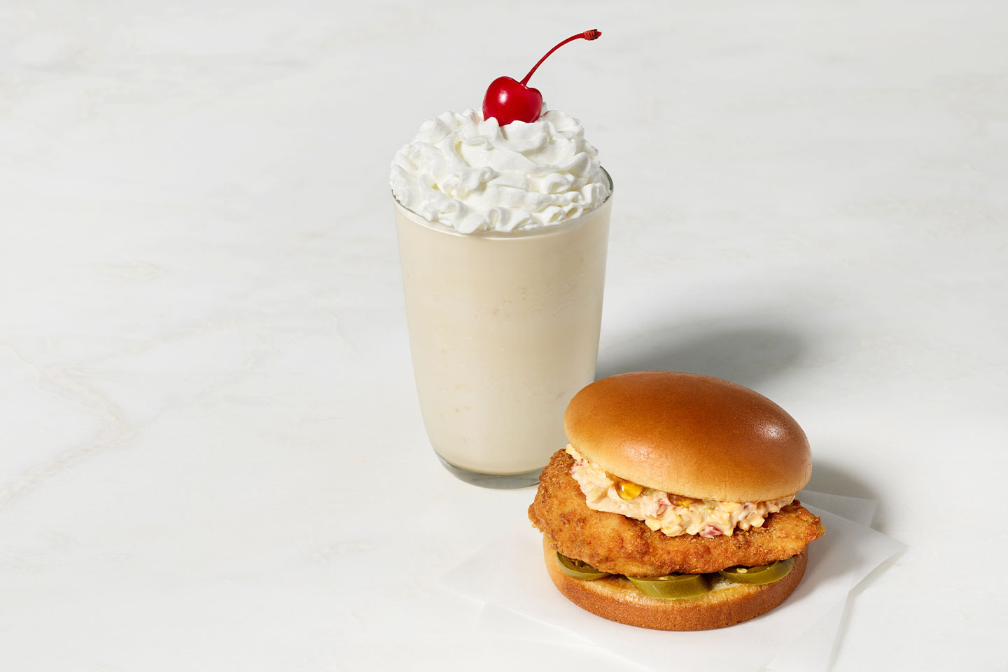 a milk shake and chicken burger on a bun.