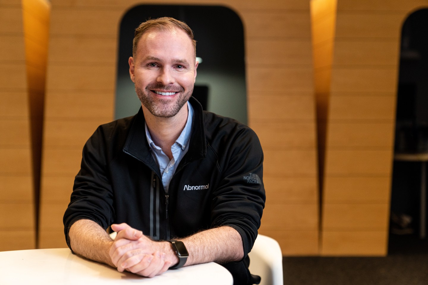 man in fleece jacket smiling with hands folded