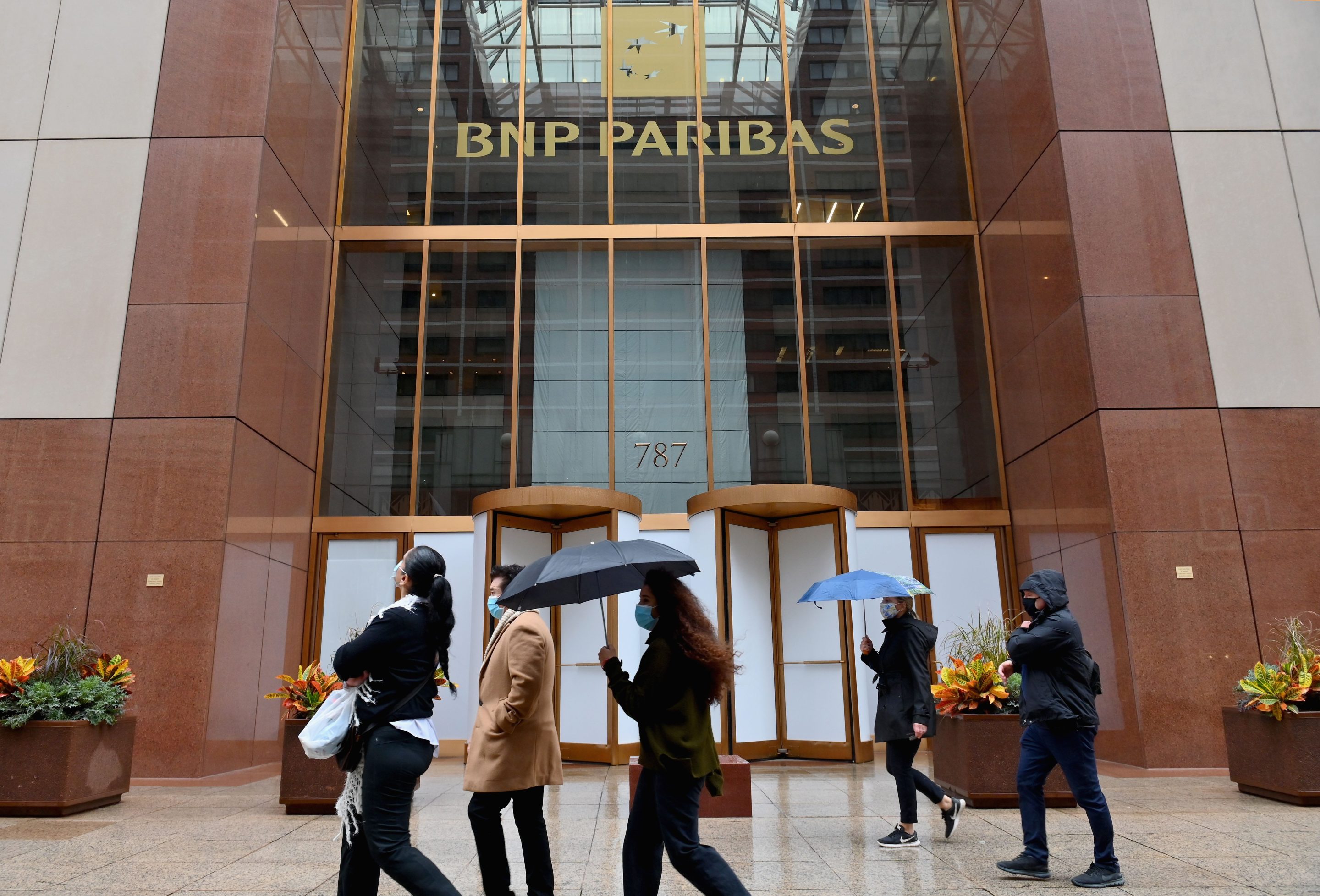 Workers pass outside a BNP Paribas bank