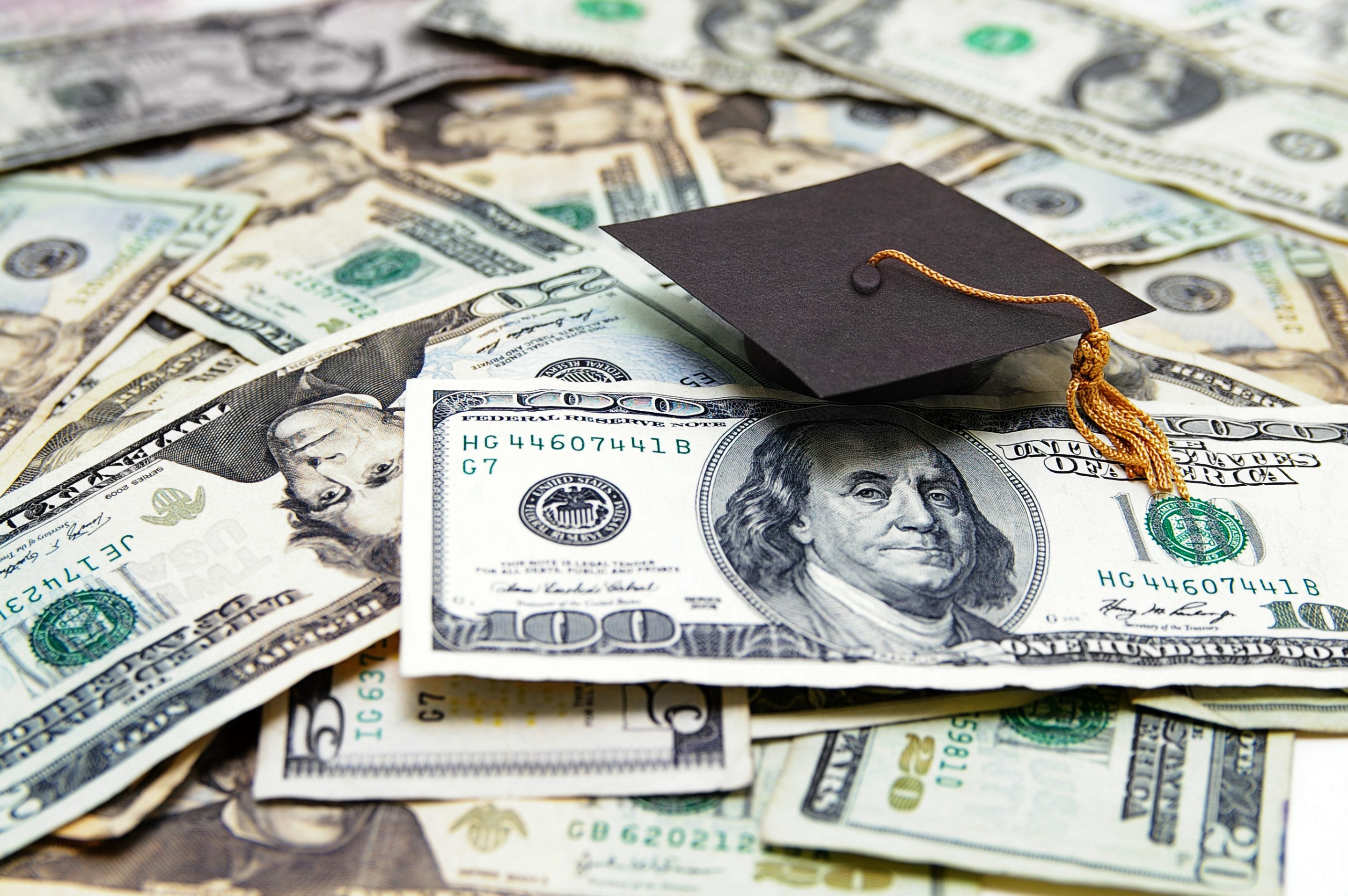 A mini graduation cap sitting on dollar bills