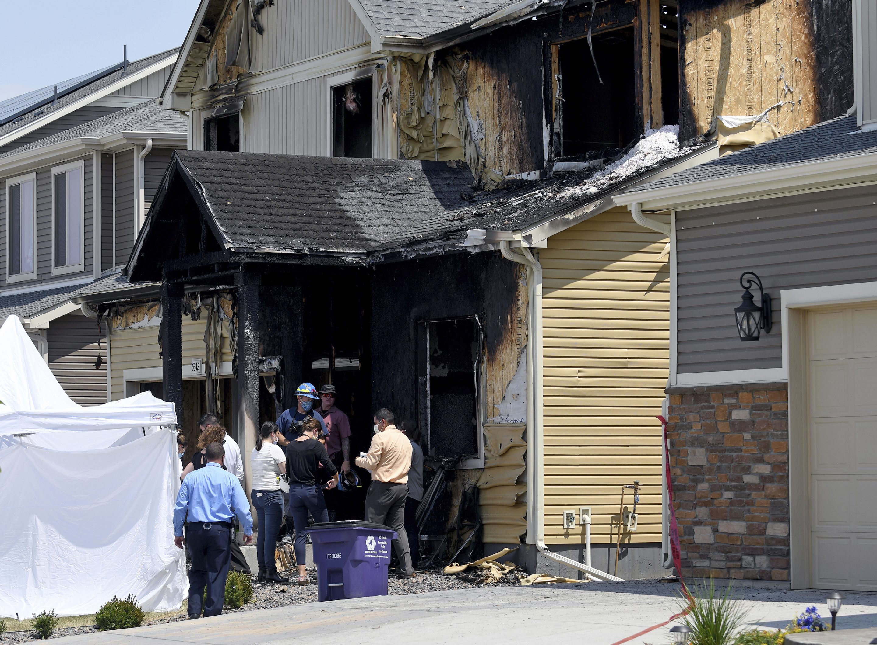 Investigators stand outside a house where five people, immigrants from the West African nation of Senegal, were found dead after a fire, Aug. 5, 2020, in Denver. 