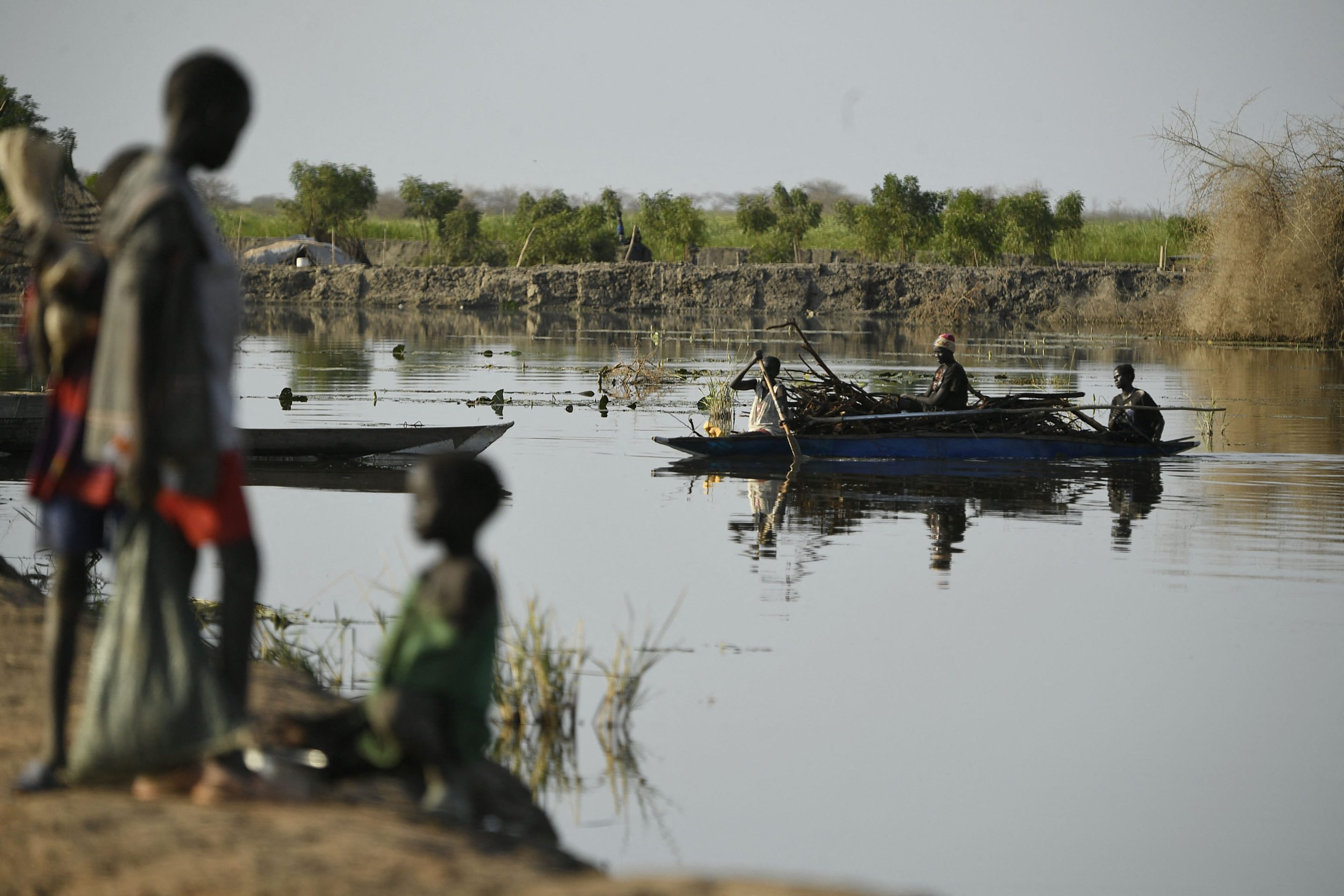 Displaced women transport firewood as they wade through flood water in South Sudan after four straight years of flooding linked to climate change swamped two-thirds of the country.
