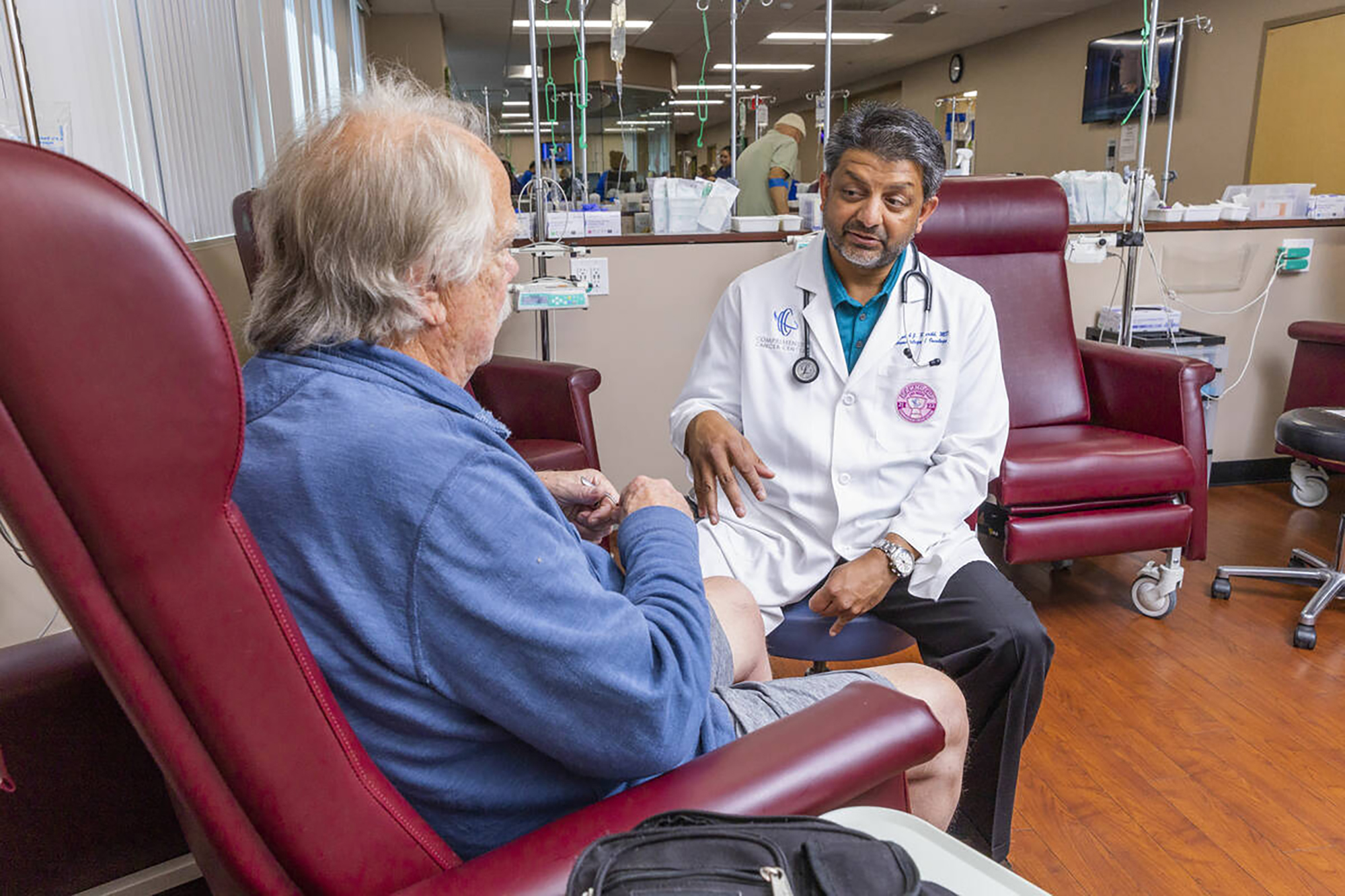 Dr. Rupesh Parikh, right, chats with patient Scott Long of Las Vegas in the chemo treatment room at the Comprehensive Cancer Centers on May 18, 2023, in Henderson, Nevada. 