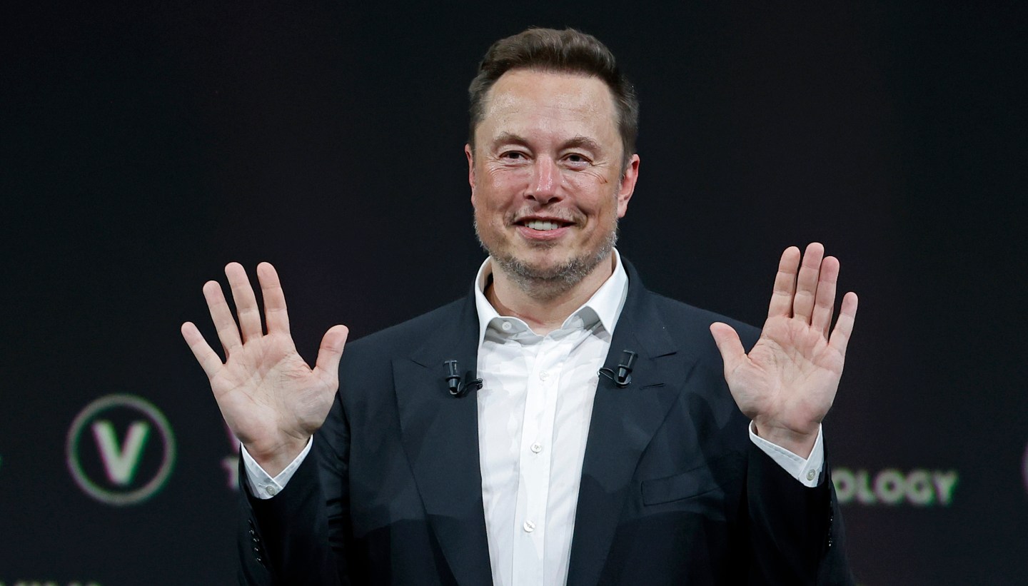 Elon Musk holding hands up