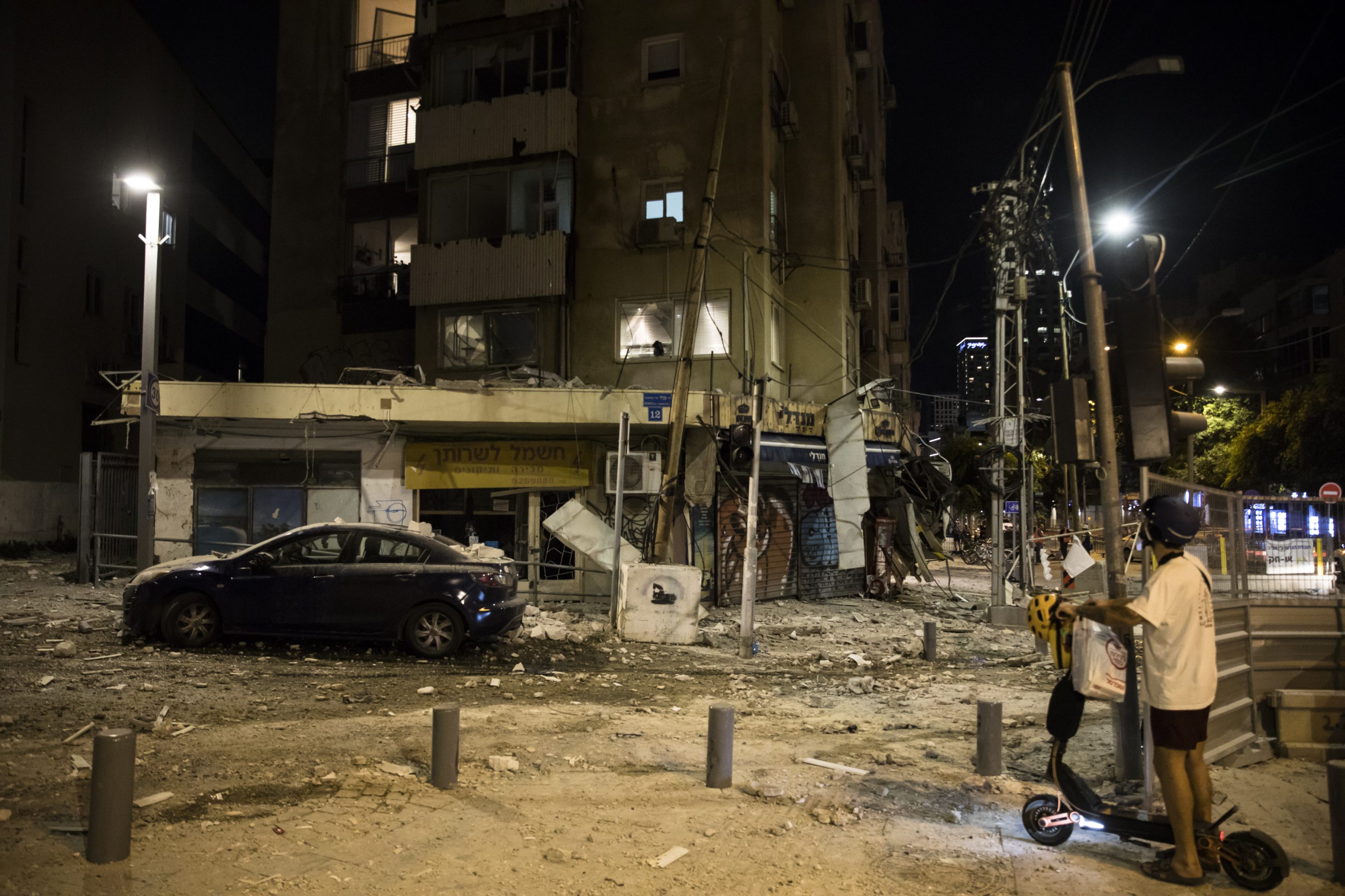 A man passes the scene where a rocket fired from Gaza strip hit a building on October 7, 2023 in Tel Aviv, Israel.