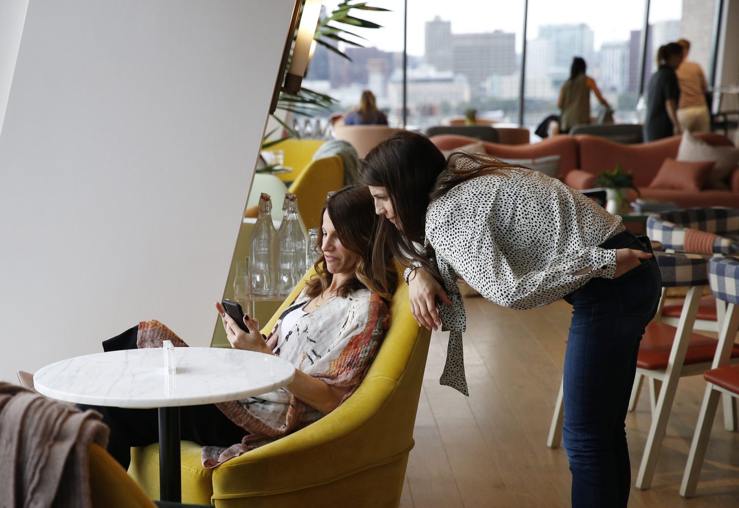 two women sit in an open office area
