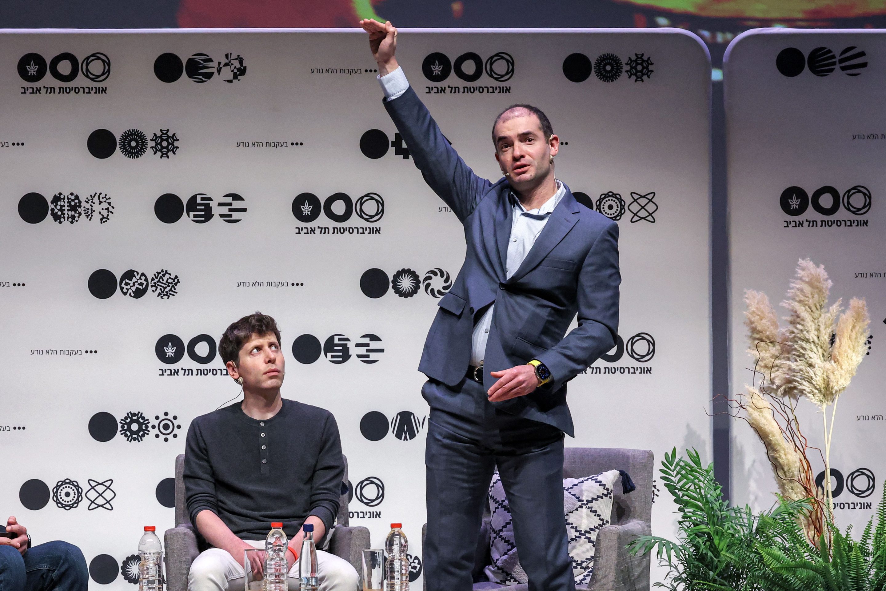 Ilya Sutskever (standing) and Sam Altman speak at Tel Aviv University on June 5, 2023.