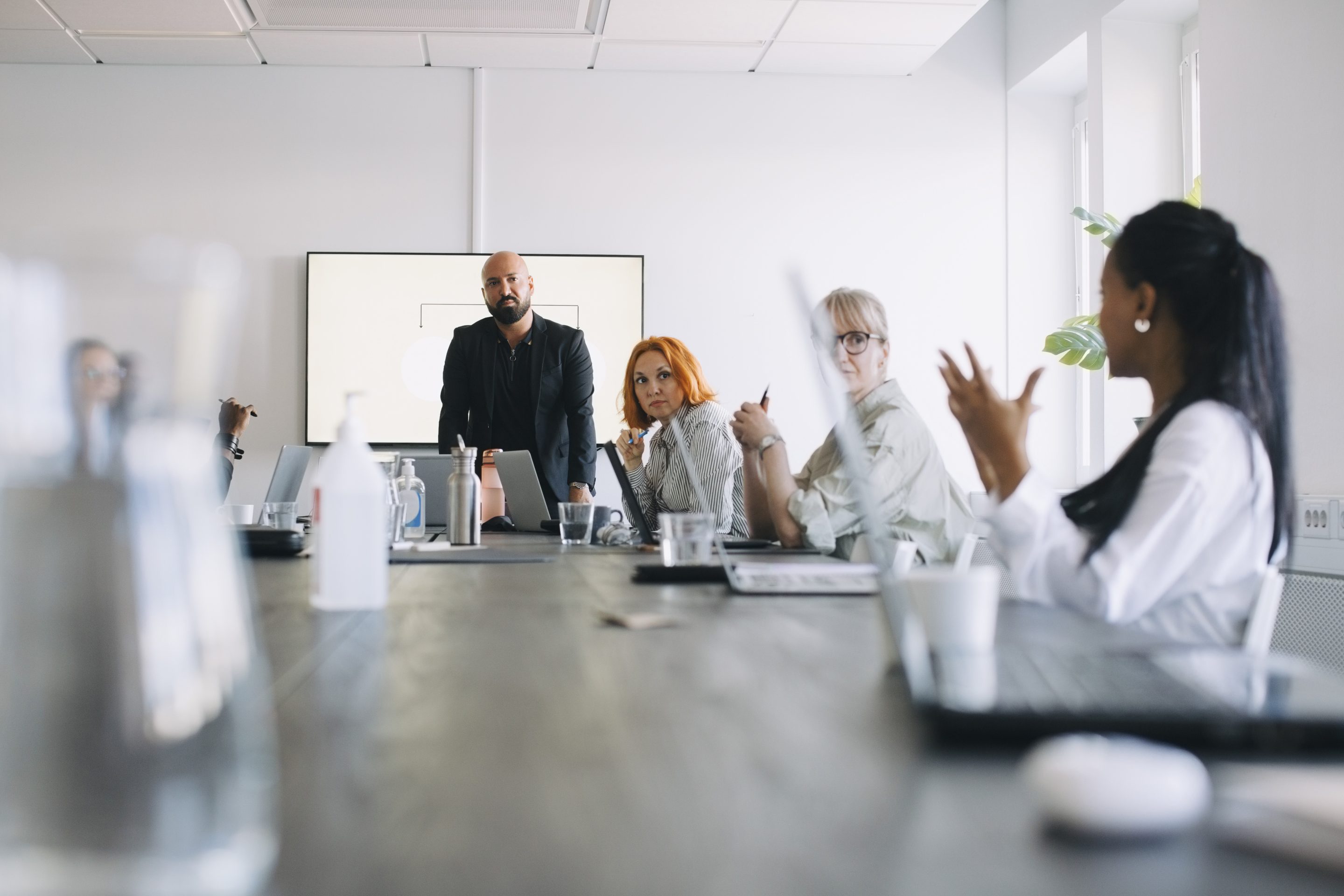 Businesswoman sharing ideas with male and female colleagues in board room.
