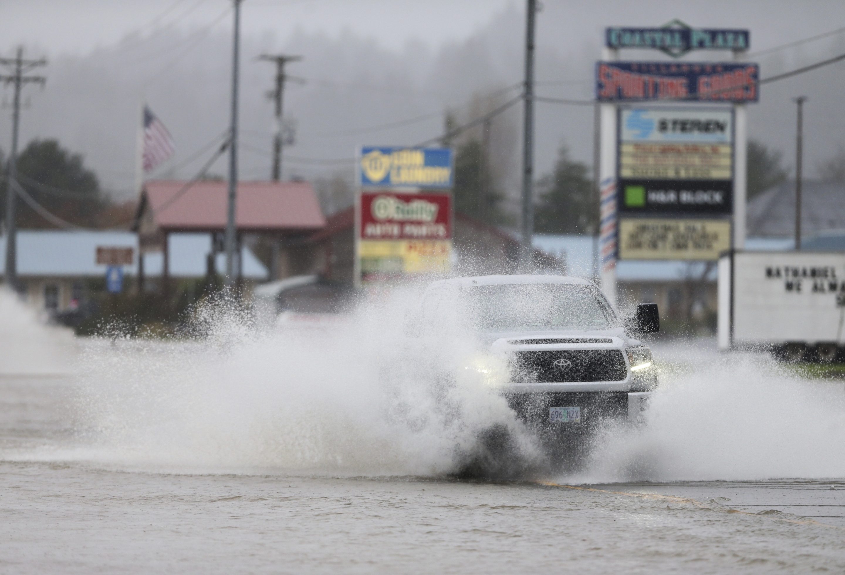 A car driving through water on a flooded highway