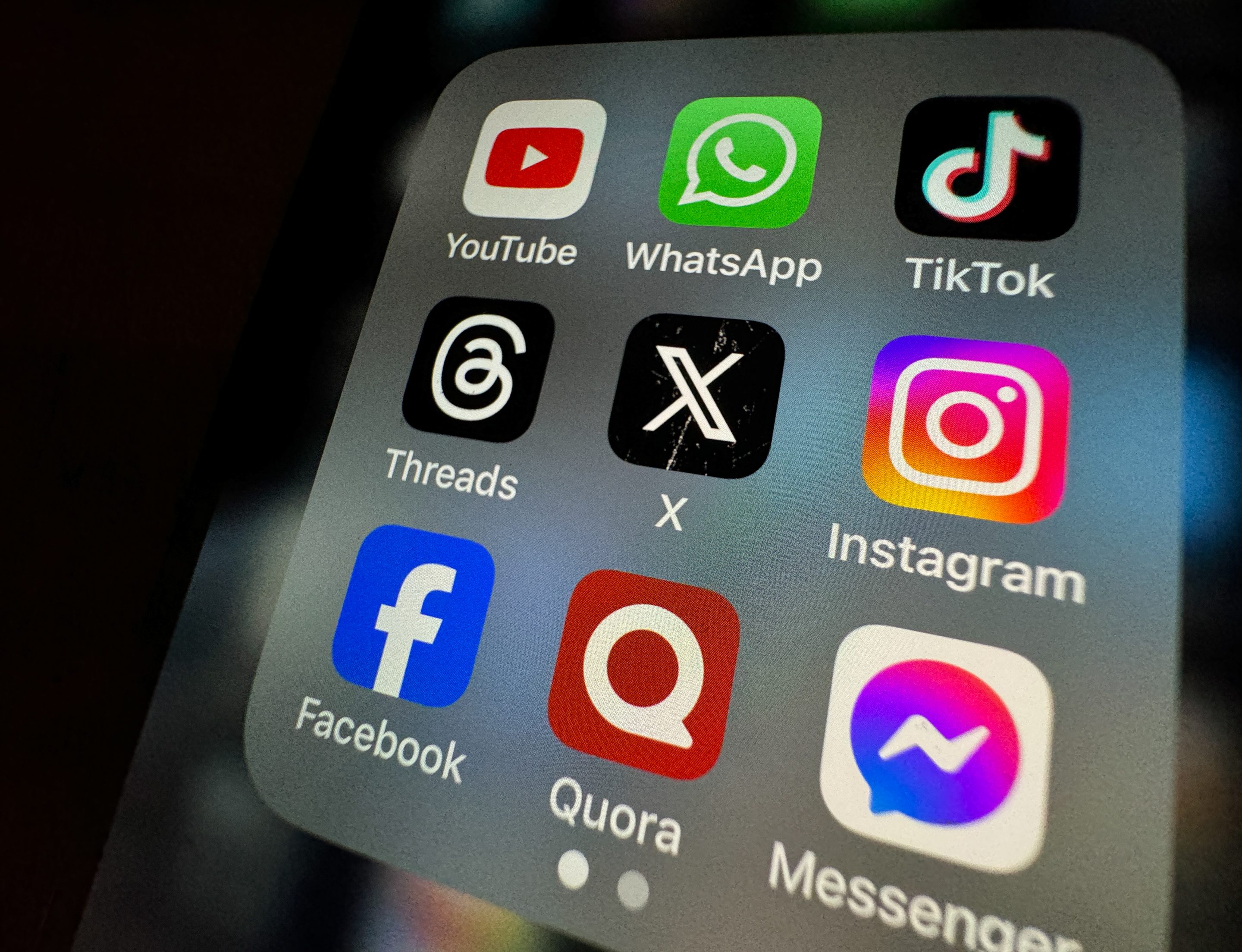 photo illustration the logo of US online social media and social networking site 'X' (formerly known as Twitter) is displayed centrally on a smartphone screen alongside that of Threads (L) and Instagram (R)