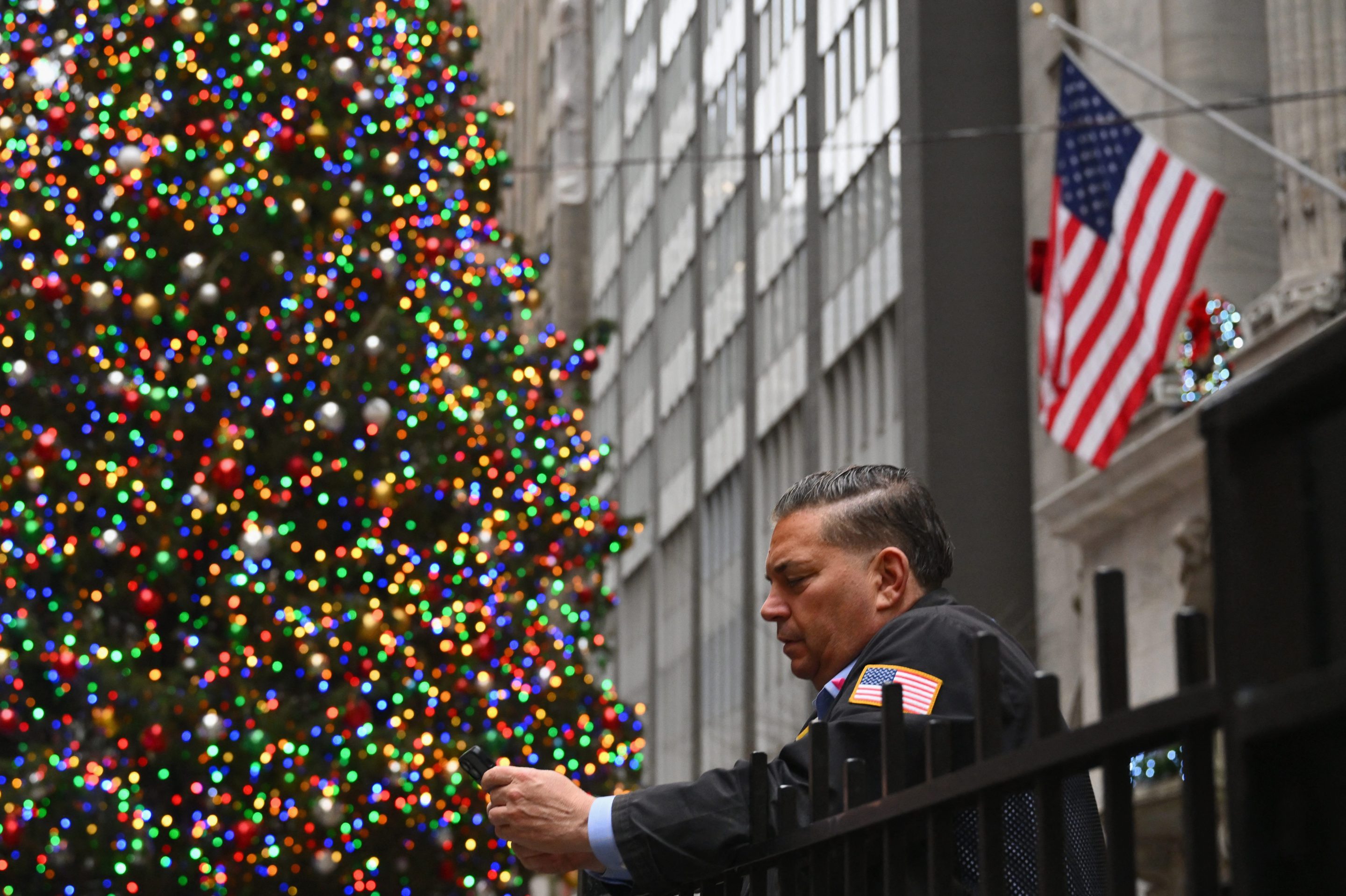 A trader looks at his phone outside of the New York Stock Exchange (NYSE) in New York on December 1, 2023.